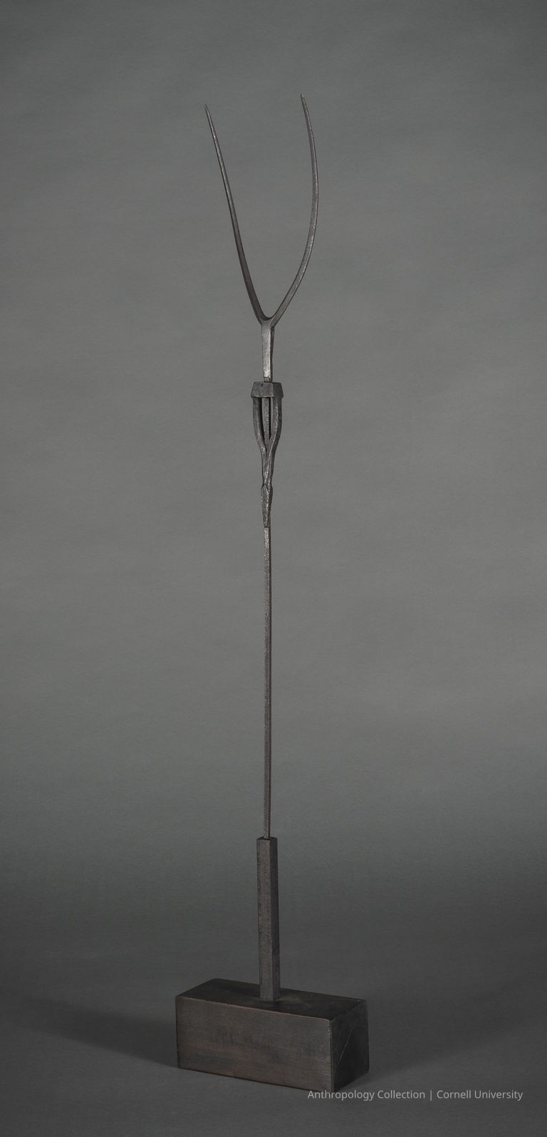 VOTIVE FIGURE | circa 1960-65 | Photo by Ann Cady, 2024 | ©2026 Norman Daly Art — A sculptural object consisting of a black, slender, elongated metal rod extending vertically from a solid, rectangular black wooden base; atop the rod is a delicate, wishbone-like structure.