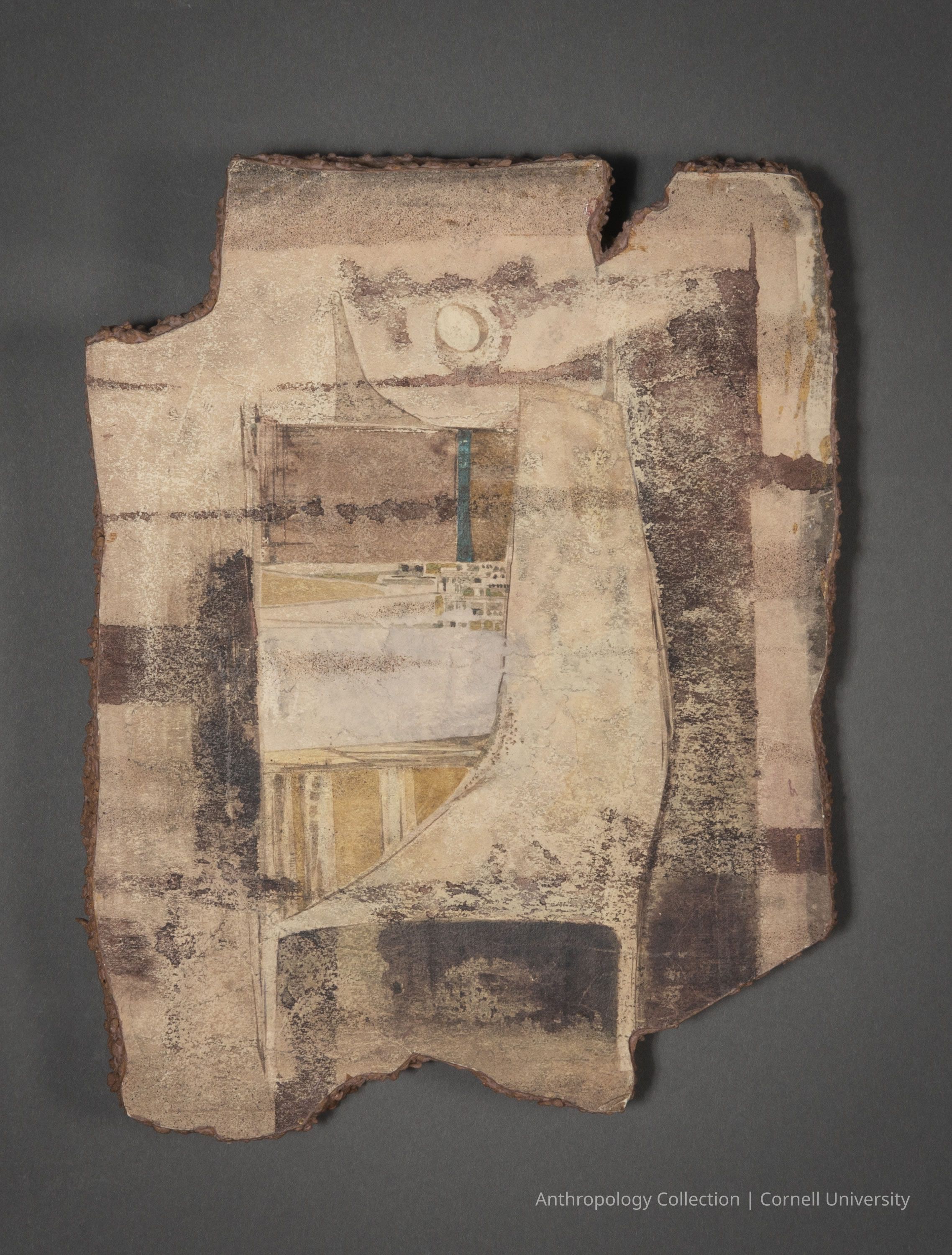 FRAGMENT OF WALL PAINTING FROM TEMPLE OF PHALLOS AT DRAIKUM | 1966-71 | Photo by Ann Cady, 2024 | ©2026 Norman Daly Art: A rough jagged piece of a fragment of a fresco. It features layered shapes and lines in earthy tones like beige, brown, and cream, with sections of blue and gold adding subtle contrast. In the center, a curved shape suggests movement, while the piece appears aged and weathered, evoking a sense of history and antiquity.