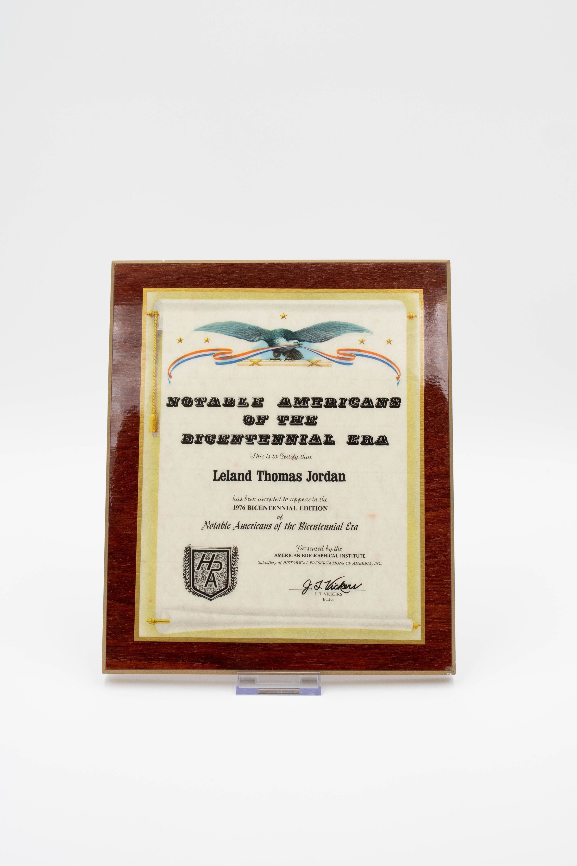 Notable Americans of the Bicentennial Era Certificate: Image of a plaque that recognizes Leland Thomas Jordan as a notable American in the Bicentennial Era. The surface of the certificate has a sheen and it has a brown wood border. An eagle with its wings stretched out and with a red, white, and blue banner in its beak accompanies the top of the certificate.