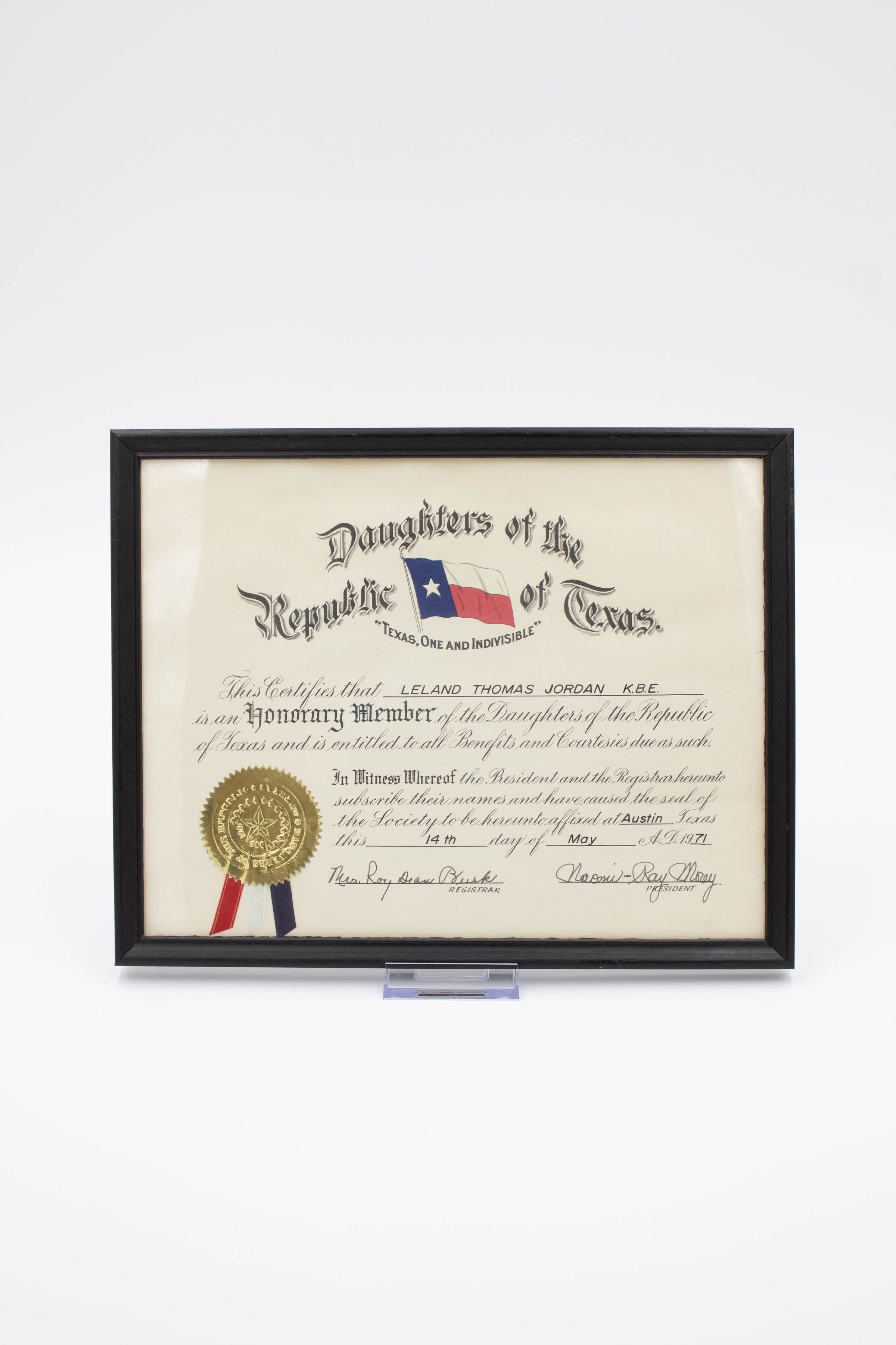Daughters of the Republic of Texas Honorary Member Certificate: Image of the certificate in its glass case. In a cursive script the certificate reads "This Certifies that Leland Thomas Jordan K.B.E. is an Honorary Member of the Daughters of the Republic of Texas and is entitled to all Benefits and Courtesies due as such. In Witness Whereof the President and Registrar hereunto subscribe their names and have caused the seal of the Society to be hereunto affixed at Austin Texas this 14th day of May A.D. 1971."