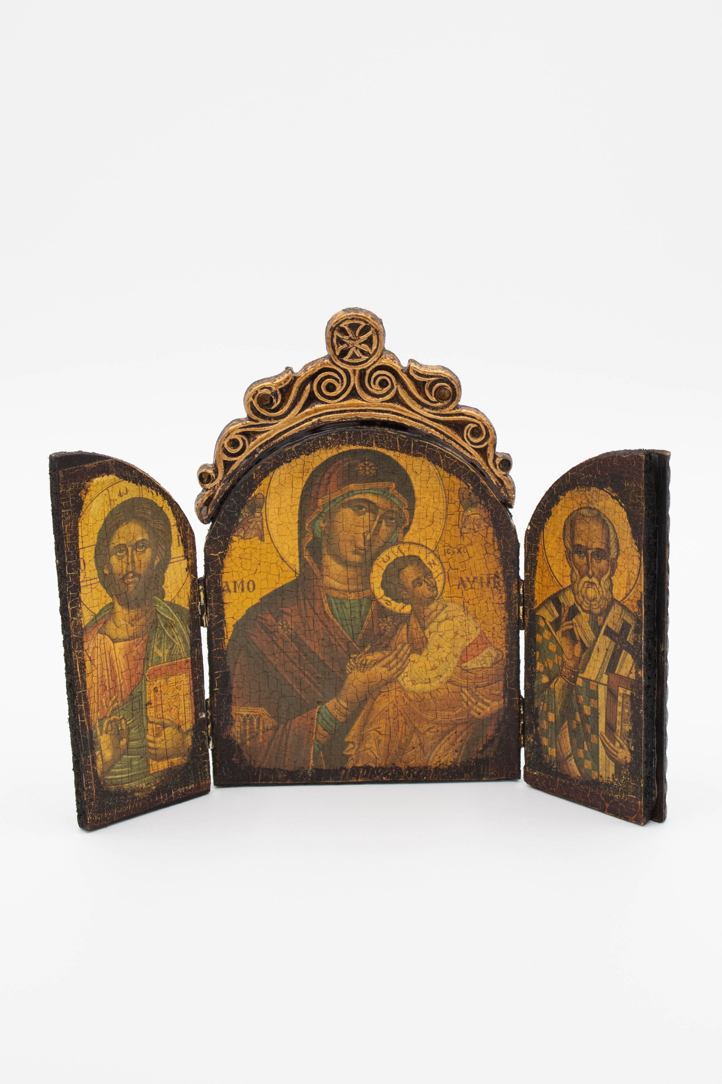 Wooden Religious Triptych: Image of the wooden triptych with both doors open. The center panel has a painting of Madonna and Child, while the left door is a depiction of Jesus and Christ and the right door is of St. Peter. The paintings are in a Late Byzantine style and are heavily aged. Above the center panel is a wooden crown with a cross.