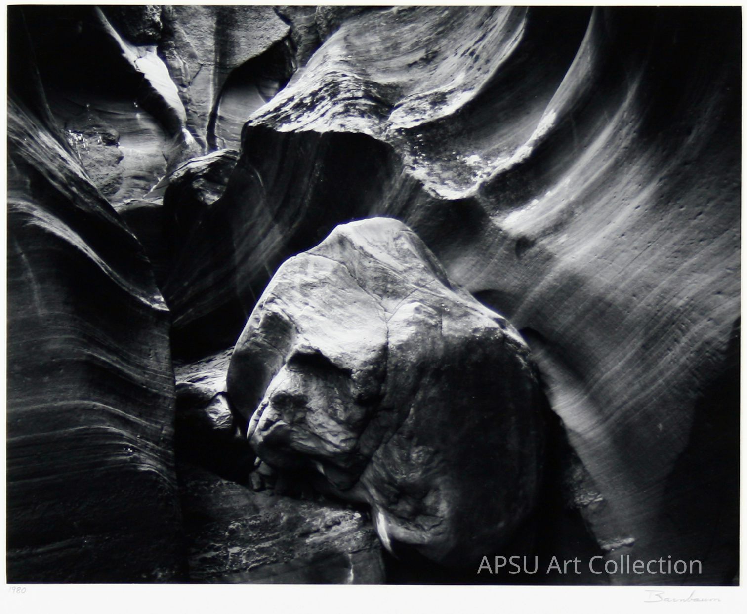 This black-and-white photograph captures the intricate and textured landscape of a rocky canyon, where smooth, flowing lines of eroded rock surfaces create a captivating natural abstract pattern, emphasizing the play of light and shadow on the varied surfaces, highlighting the unique formations of the canyon walls and the large central boulder nestled among them, taken by a photographer noted for capturing the sublime beauty of nature with a keen eye for detail, bringing attention to the intimate and often overlooked nuances present in rugged wilderness environments.