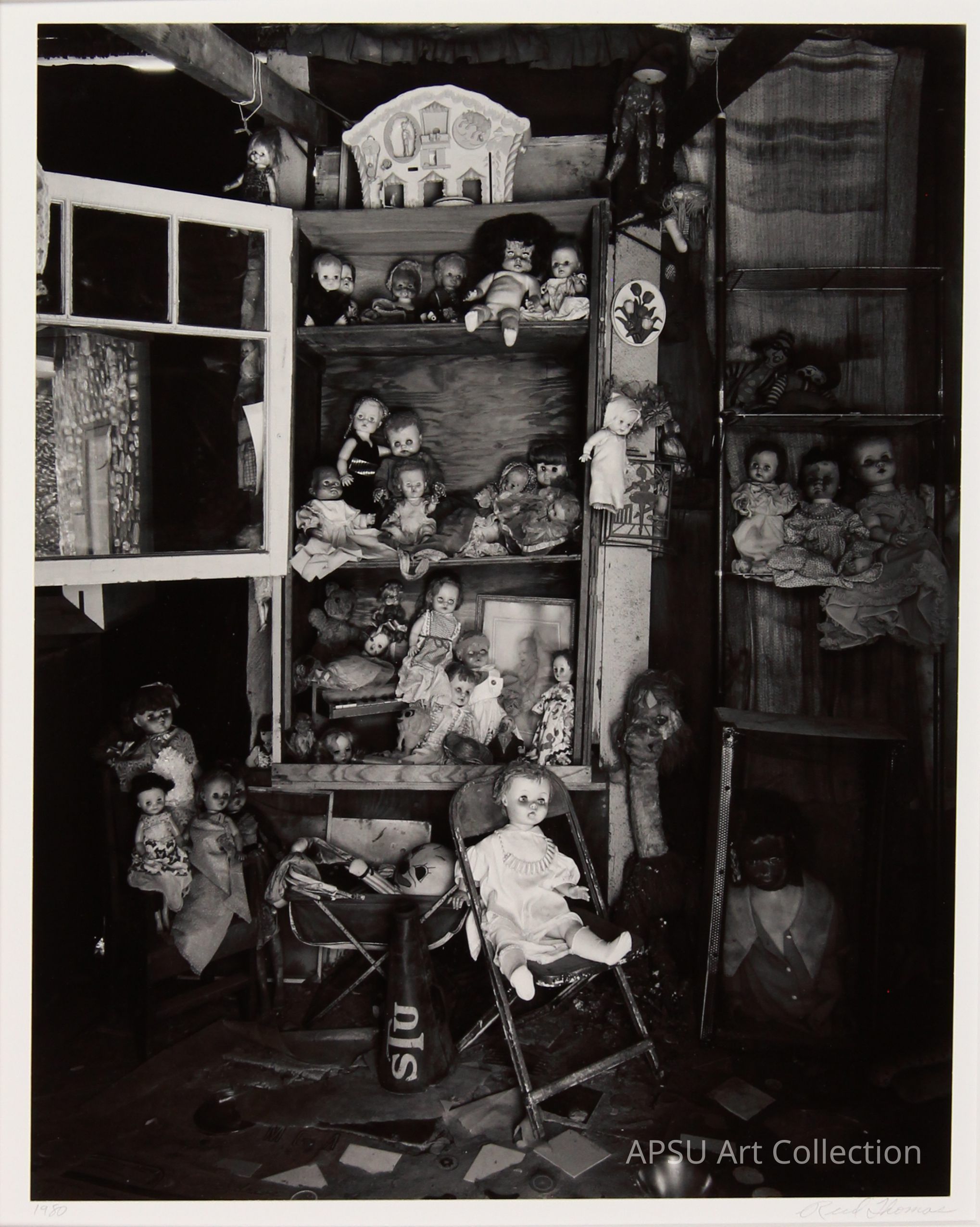 The image presents a hauntingly arranged collection of various dolls and figurines, some placed in cabinets and others scattered amidst debris in a cluttered, dimly lit room. Disarray and neglect characterize the scene, accentuated by a number of dolls in different states of wear and position, contributing to an eerie, abandoned atmosphere. The diverse array of dolls, from porcelain to cloth-bodied, some seated and others standing, evokes a strong sense of nostalgia mixed with melancholy.