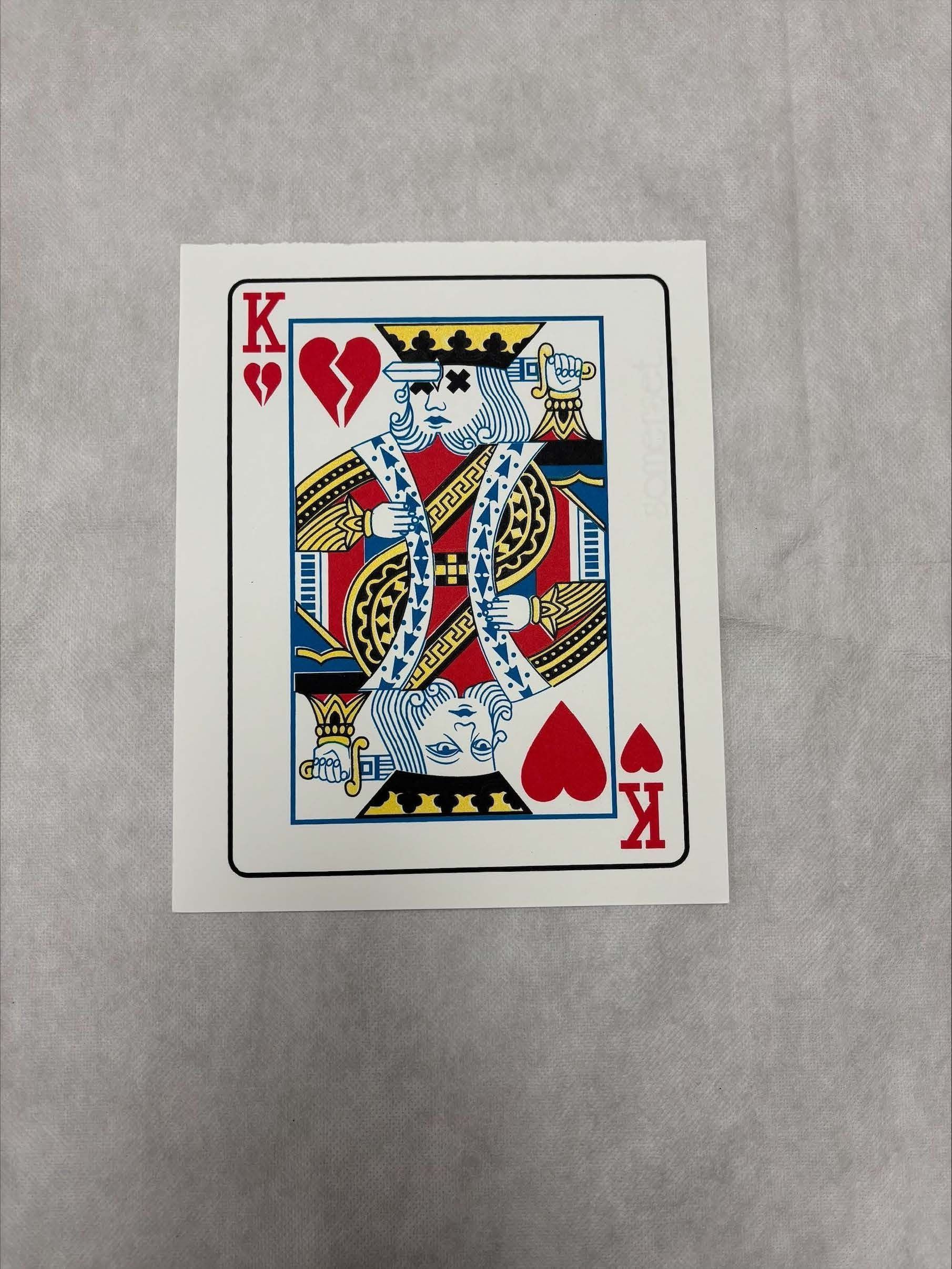 Front: A vertically oriented, medium sized print that uses the colors red, black, blue, yellow and white to create that image presented in the print. The print is done on a white ground and mimics a king of hearts playing card that is seen in a traditional deck of cards. However, one on the images of the king seen of the card inserts a blade through his forehead which is not a motif seen on a traditional card.