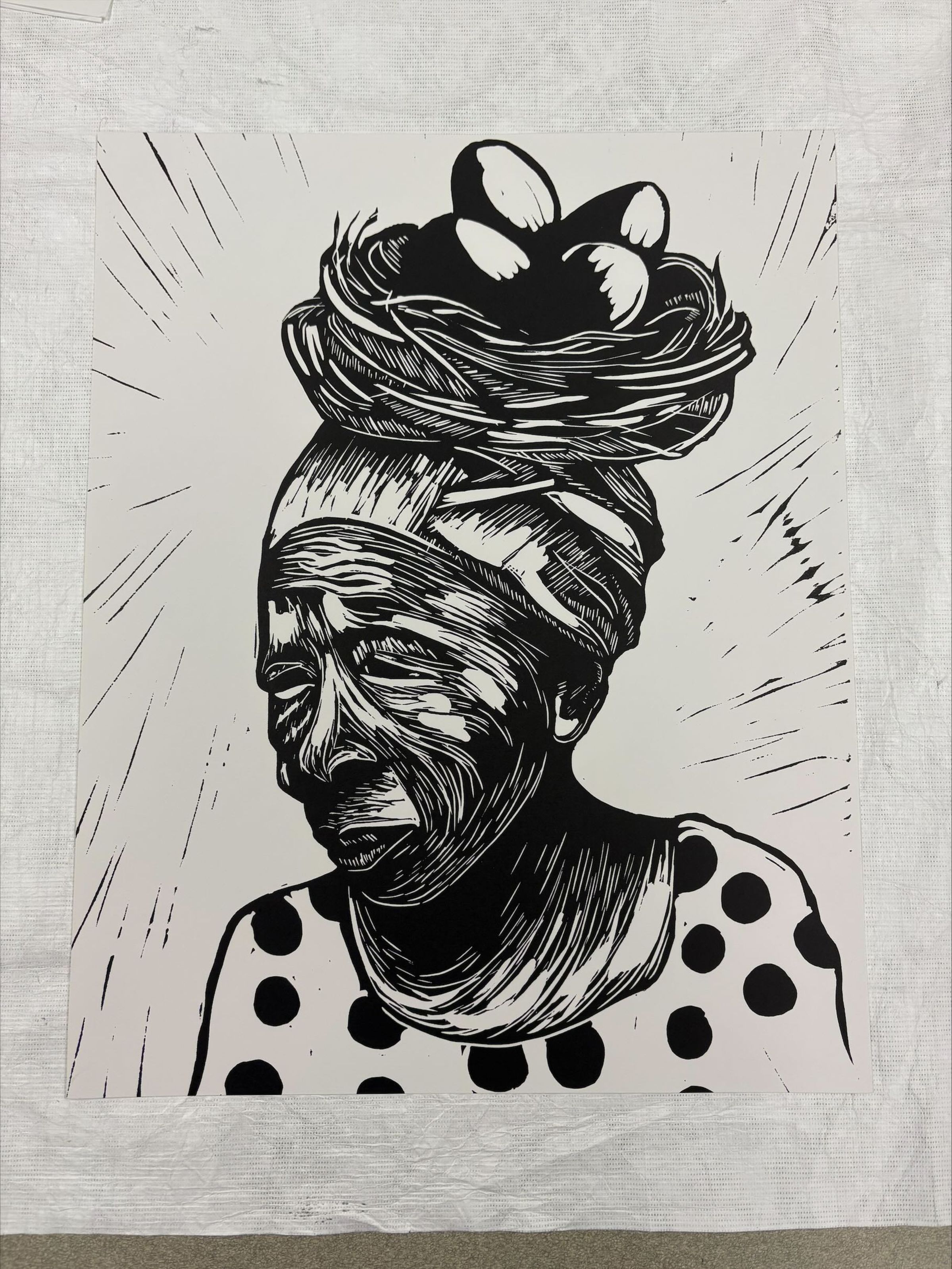Front: A vertically oriented, medium sized print that is minimalistic in its use of color using only black and white to create the image. The print depicts an older African American woman, cropped just below the shoulders, carrying a basket on top of her head.