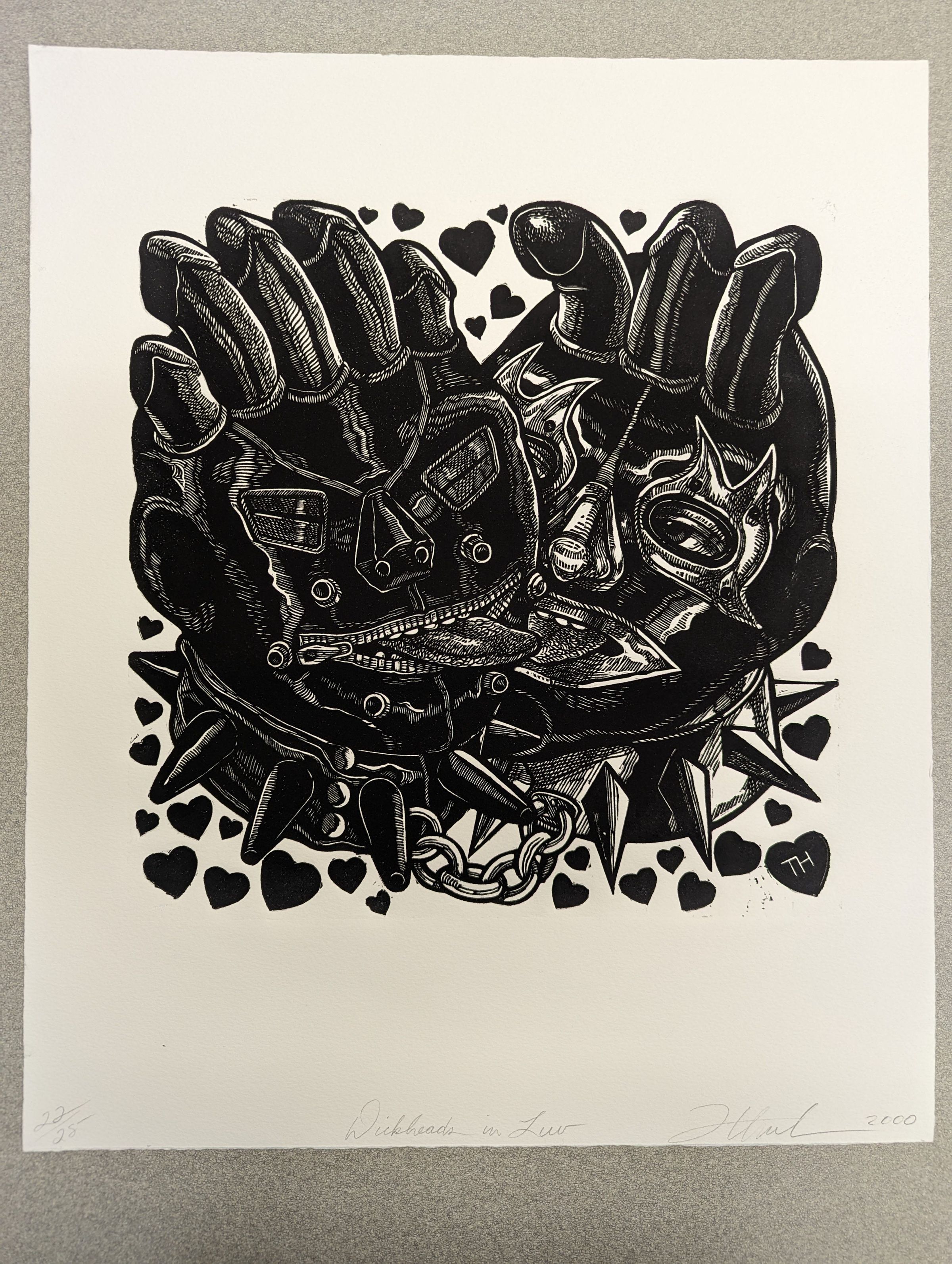 Front of print: A large intaglio print of two figures wearing full-coverage head masks with openings for their eyes and mouths. The figures are chained together by their spiked collars and kiss while heart shapes float around them. Their masks are crowned with phalluses (the left figure has five, the right figure has three).