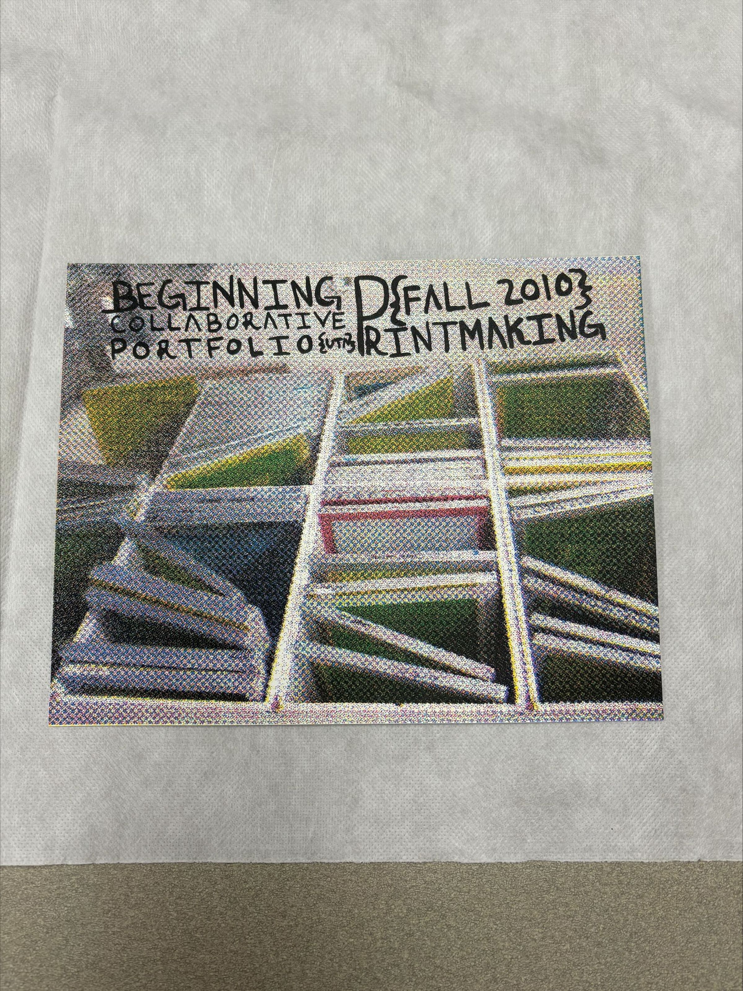 Front: A medium sized print that is horizontally oriented on the front and vertically oriented on the back. The print is multicolored and is created using both imagery and text, the front illustrates a collection of multicolored books in boxes. While the back of the print has the names of artist contributing to this portfolio.