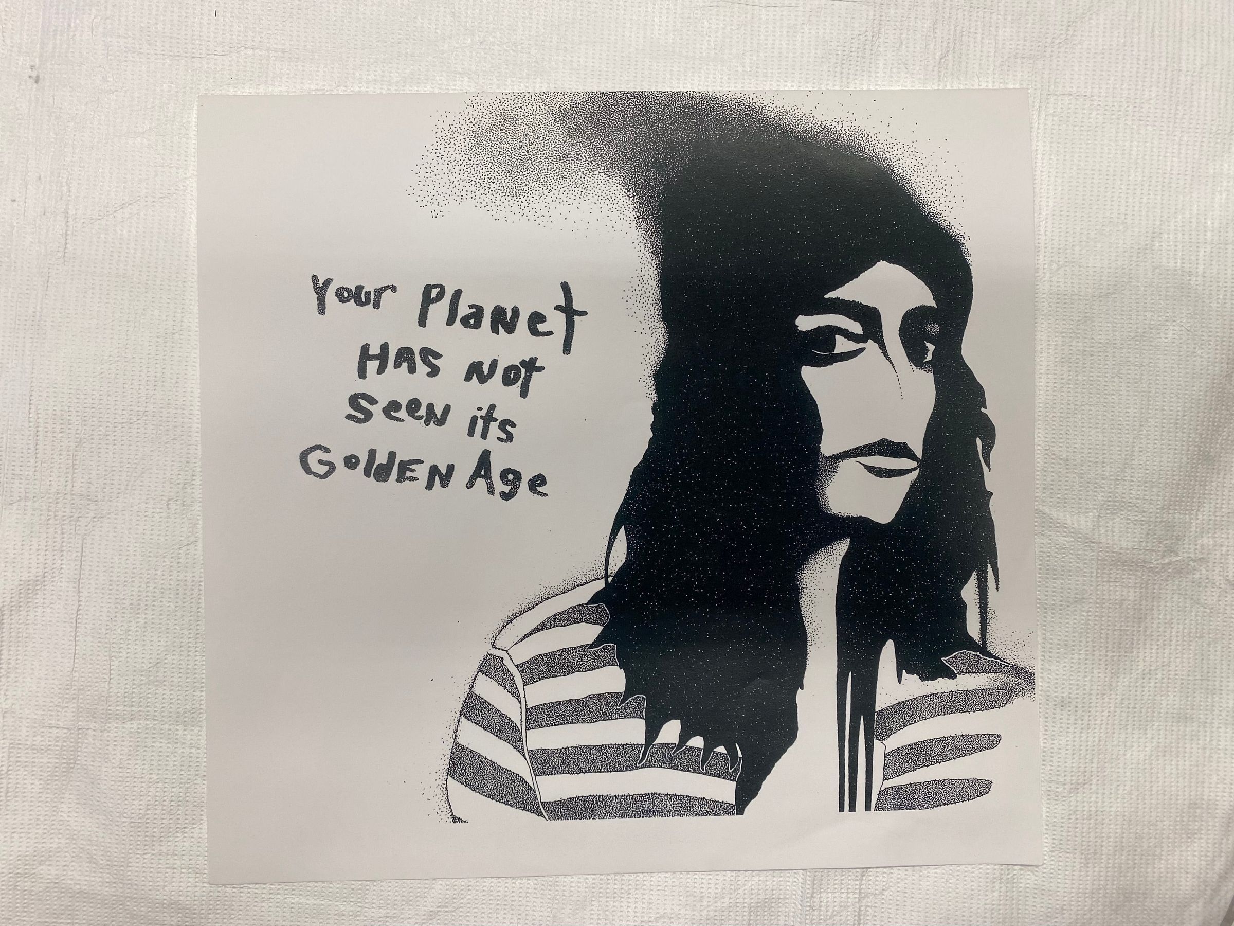 Your Planet Has Not Seen Its Golden Age (3rd Printing): Small photocopy print folded into a booklet with four internal circular prints. The external booklet on the front has a printed image of a centrally placed female figure in profile with long black hair in a striped shirt with the title of the work on the right proper. The back of the booklet contains a handwritten letter from the artist to the reader and hand-stamped text across the bottom region. Each one of the internal circular shapes includes a centrally placed motif with a black space-like border with repetitive white dots. The first image is a snake-like figure twining through the bottom of the scene, surrounded by abstracted shapes in space; above are the feet of a figure with long claw-like toenails. The second image is a female figure adorning Egyptian-style clothing and adornments, smelling a flower similar to a rose. The third image is of two canine figures in profile, one black with a white eye and one white with a black eye, with arms outstretched in the act of altercation, opposing each other like the sides of a yin-yang symbol. The fourth image is of a centrally placed eye within a rectangle with rays of light emitting below it with two snakes head down flanking either side. Beneath the eye is a pyramid with a secondary black pyramid repeated beneath it in a white square. A grid-like formation surrounds the central image.