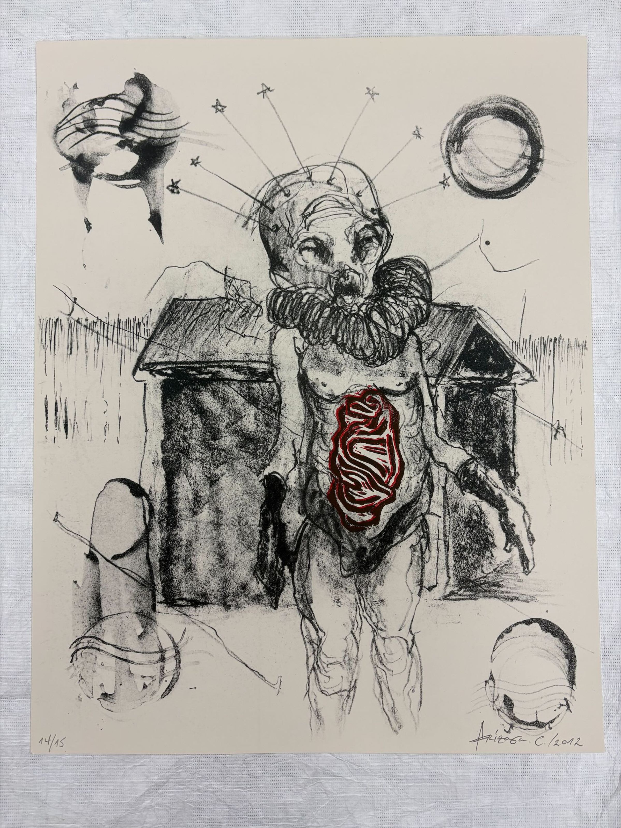 Front: A vertically oriented, medium sized print that is done on a cream colored paper with mostly grey and black pigment, although there is an accent of red around the central figures belly area. The Print is composed with a central figure that looks otherworldly, standing in front of a structure of some sort outside.