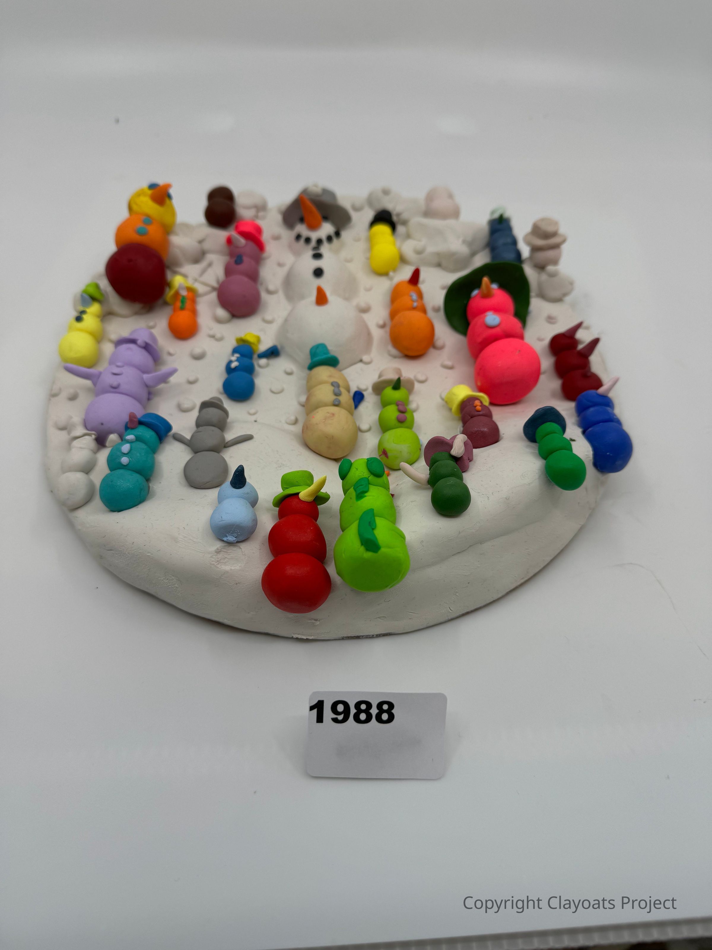 The image features a circular base covered with various colorful, miniature snowmen models made from clay or a similar material, each uniquely designed with different colors and accessories like hats and scarves, showcasing creativity and diversity among the figures; the base is labeled with the number "1988," possibly indicating the year or a catalog number for this artistic snowman collection.