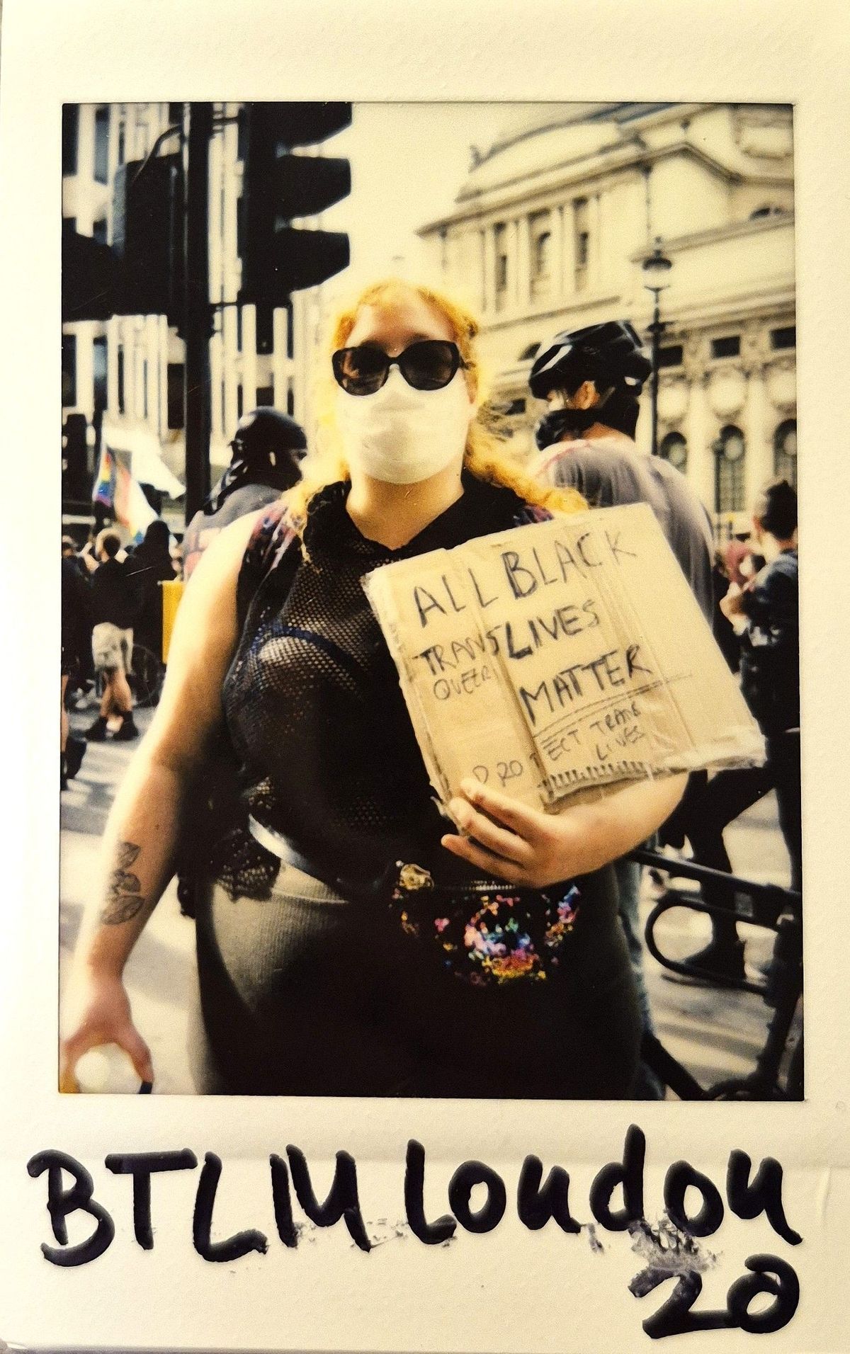 A person wearing a mask holds a sign supporting Black Trans Lives during a protest in London.