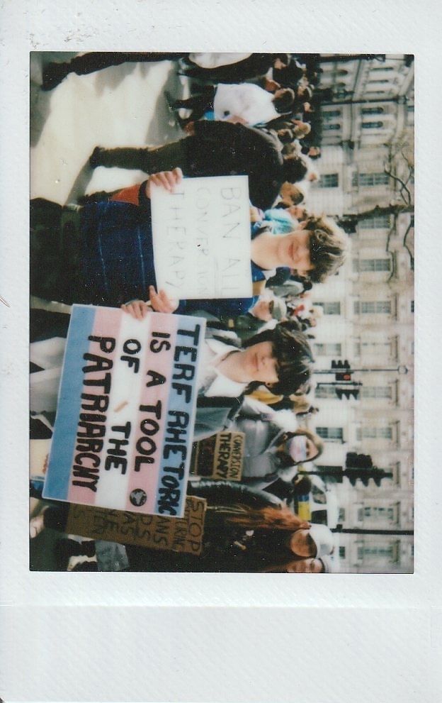 A group of people are holding protest signs, one says "TERF RHETORIC IS A TOOL FOR THE PATRIARCHY".