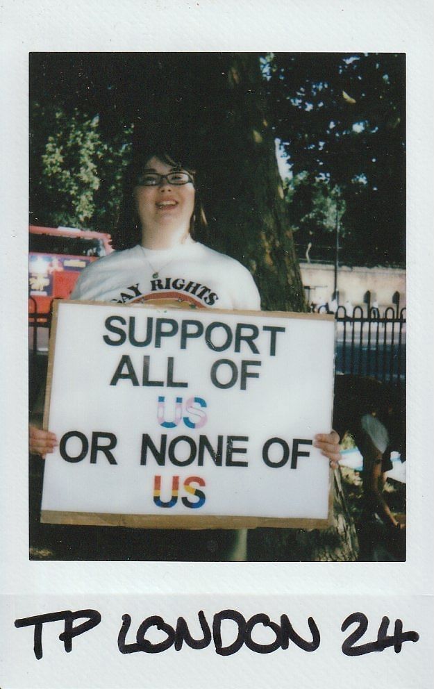 A person is holding a sign that says, "Support all of us or none of us."