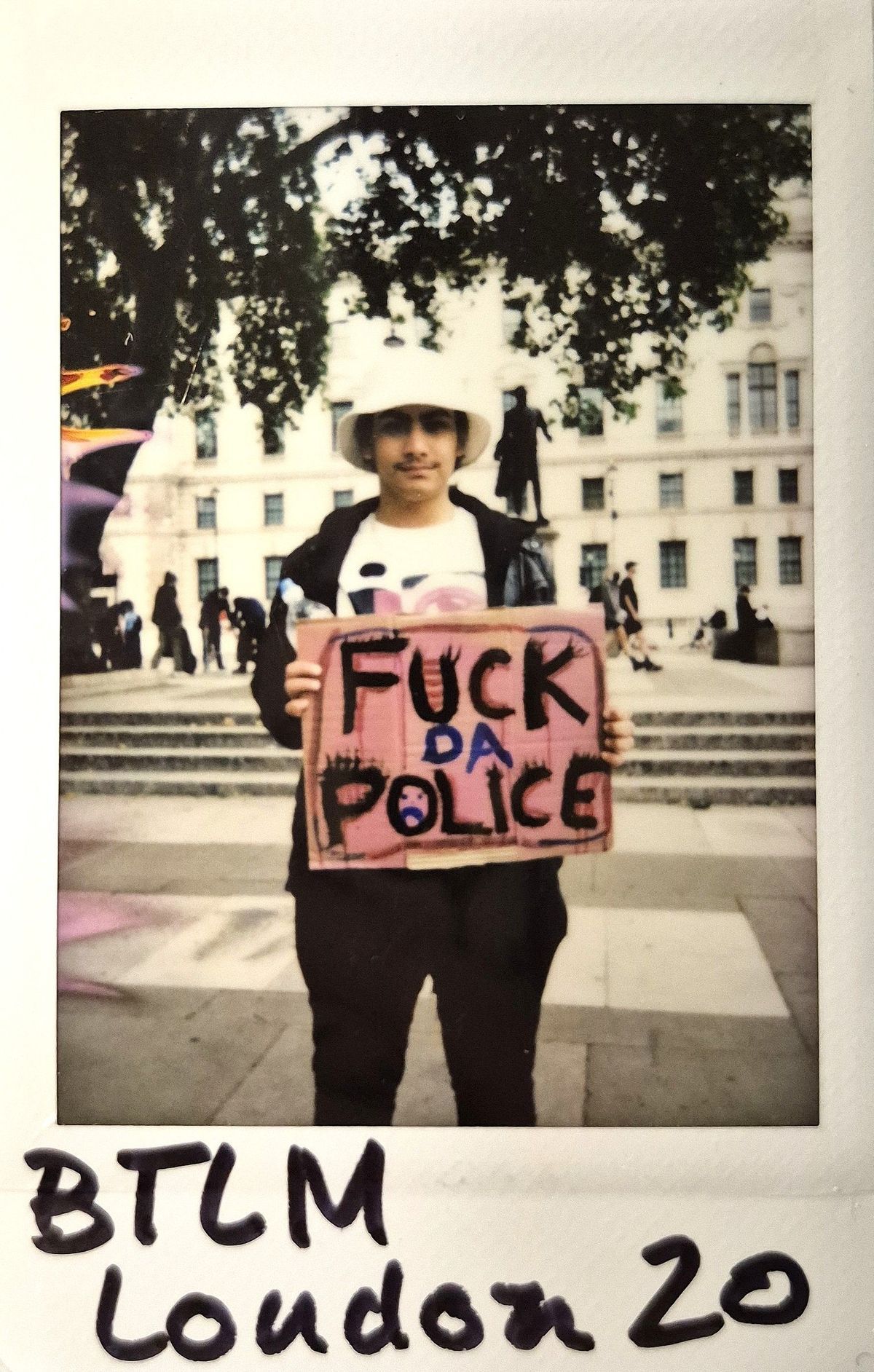 A person holds a protest sign saying "FUCK DA POLICE".