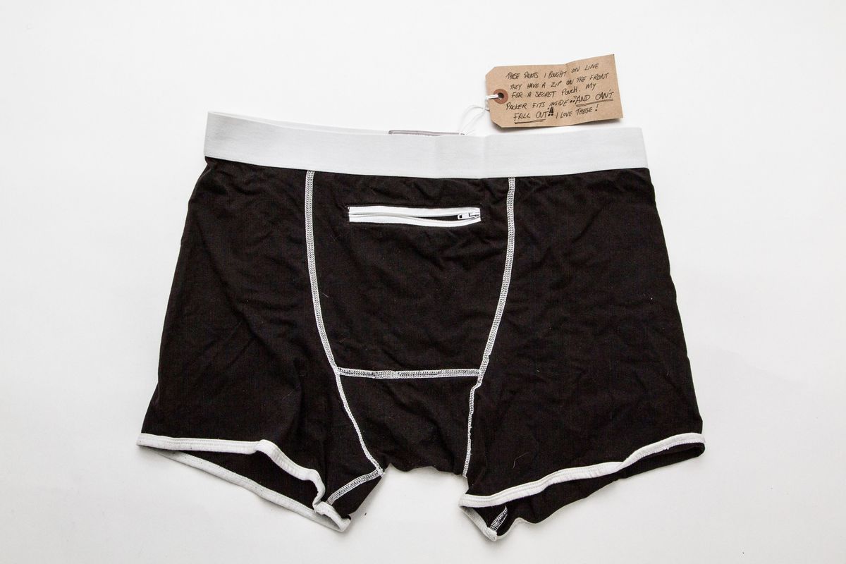 Black pants with white elastic waistband, white edging to legs & white stitching placed on a white surface. There is a white zipper pouch pocket at the front.