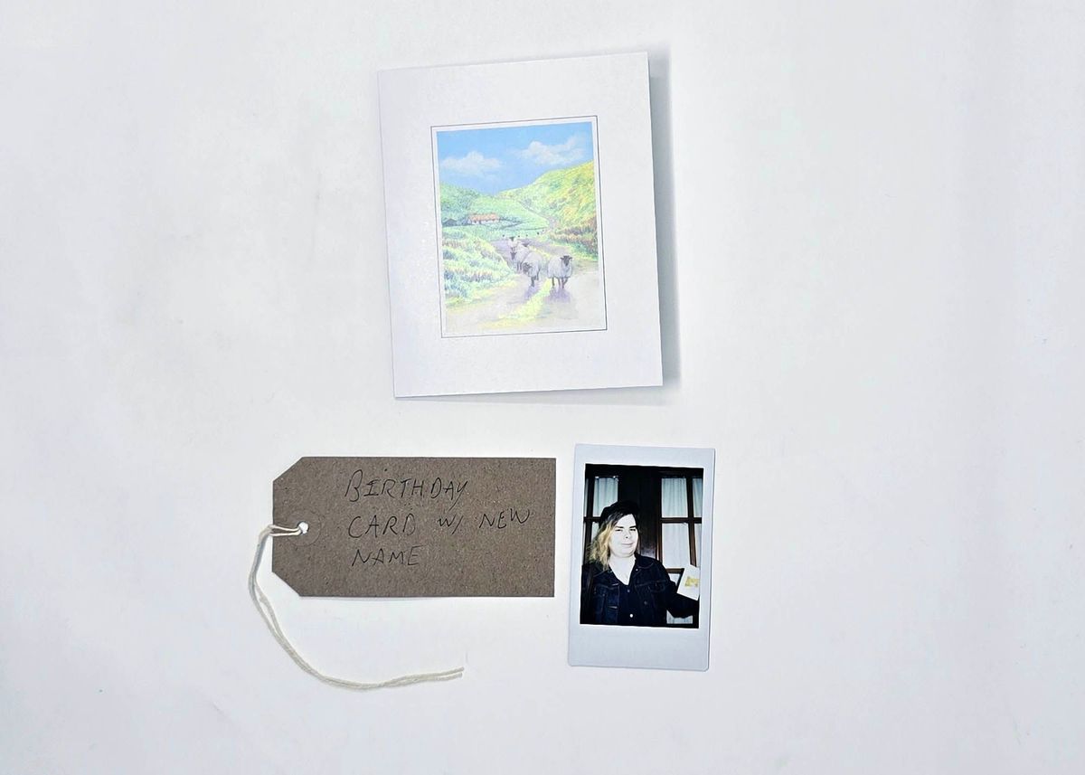 A birthday card with an illustration of sheep on a country lane. With a Polaroid and a brown, handwritten luggage tag.
