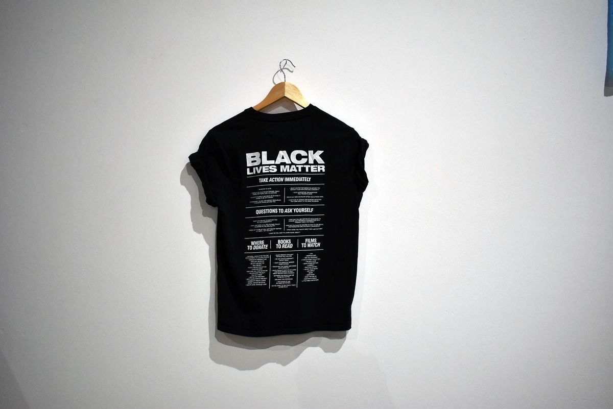 Hanging on a wall, a black T-shirt displays a "Black Lives Matter" message in bold text.