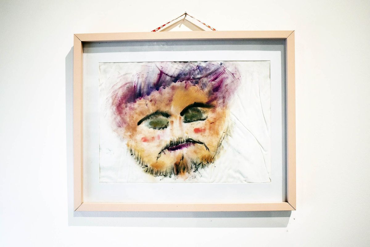 The watercolor painting displays an abstract face with closed eyes, framed with light wood.