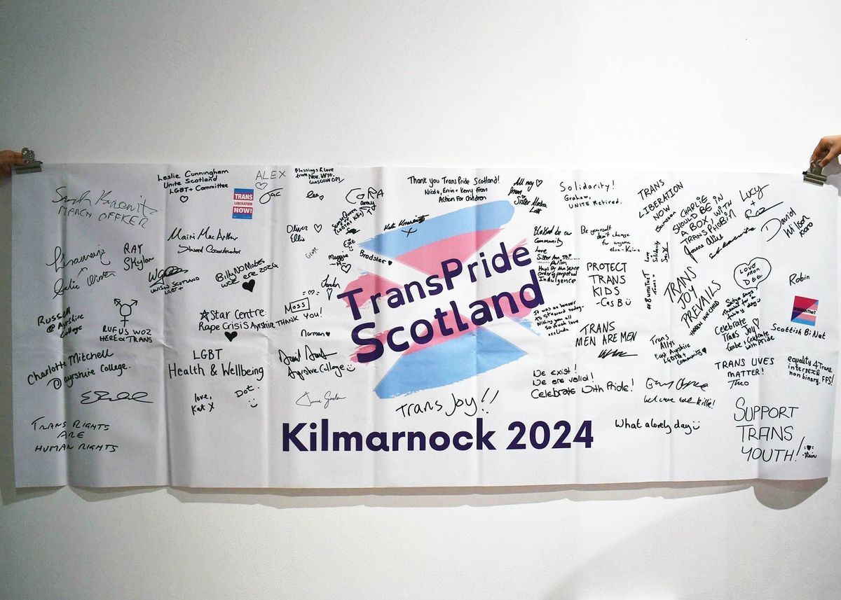 A long white vanner which is from the Trans Pride Scotland 2024 and is covered in writing and signatures.