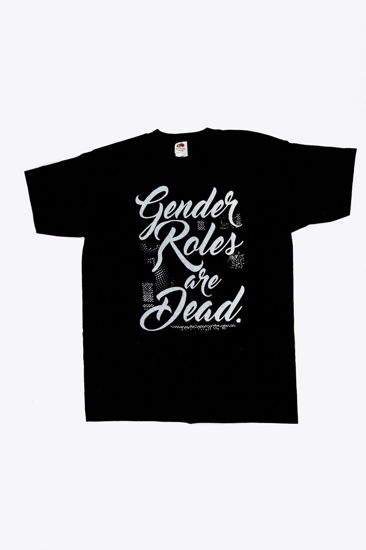 A black short sleeved t-shirt with the slogan "Gender roles are dead" printed in white cursive font. The label of the t-shirt is visible, showing the brand name "Fruit of the Loom" and size M