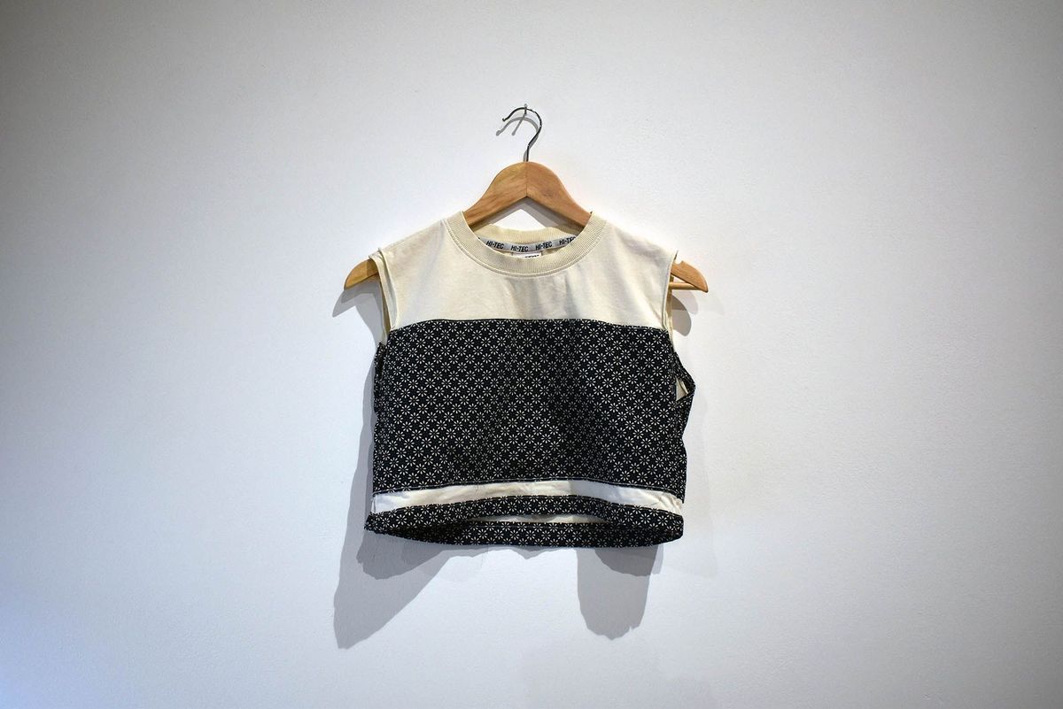 A handmade binder made from a cream shirt with a dark blue, floral patterned, material. On a wooden hanger.