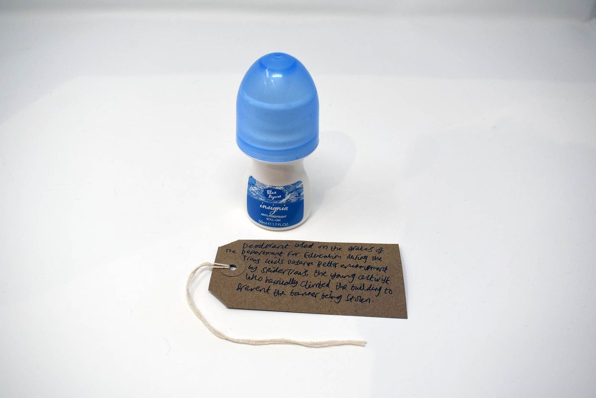 An Insignia brand roll-on deodorant. the bottle is mushroom shaped with a blue lid and a blue label. With a brown, handwritten luggage tag.