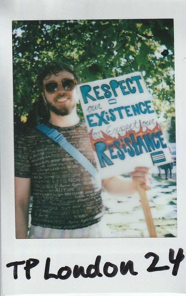 A person wearing sunglasses holds a sign that reads, "Respect our existence or expect our resistance,".