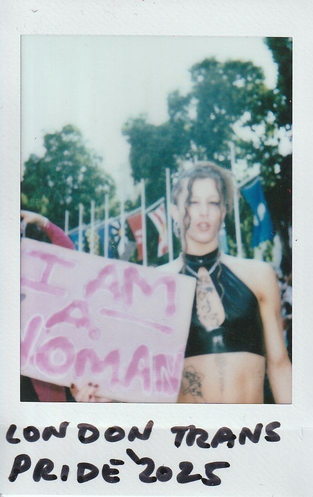A person stands holding a sign reading "I am a woman".