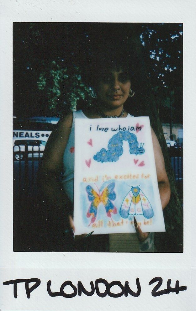A person holds a colorful artwork featuring motivational quotes about self-love and future possibilities.