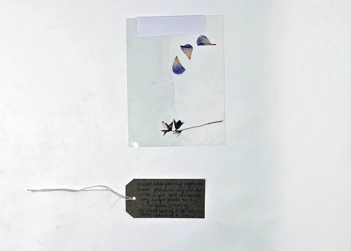 The image shows pressed flowers in plastic with a handwritten tag describing their personal significance.