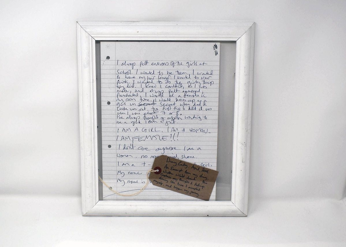 Diary entry written in blue ink, in a white frame, with a tag lying on the bottom right corner. Tag reads: "Diary Entry. April, 2012.
An Excerpt from my diary, Written Whilst drunk.... this captures my thoughts & feelings during the time I accepted myself, and began my journey....."