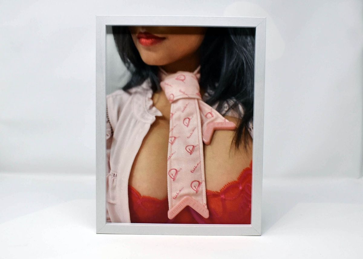 Framed colour portrait of Zakkiya Khan who has a red top on, pink jacket and pink tie.