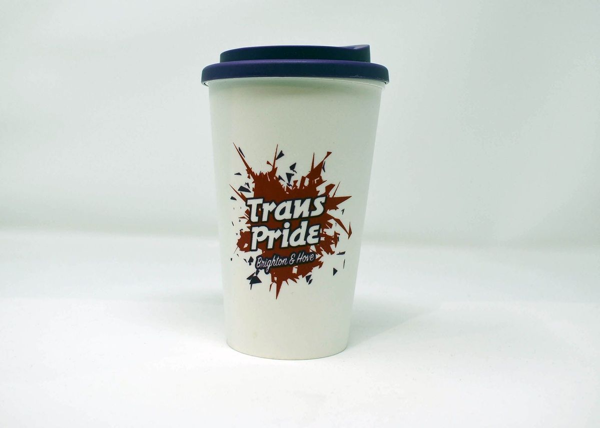 White plastic reusable coffee cup with dark purple lid. There is a red and purple logo visible on the cup which reads "Trans Pride Brighton & Hove"