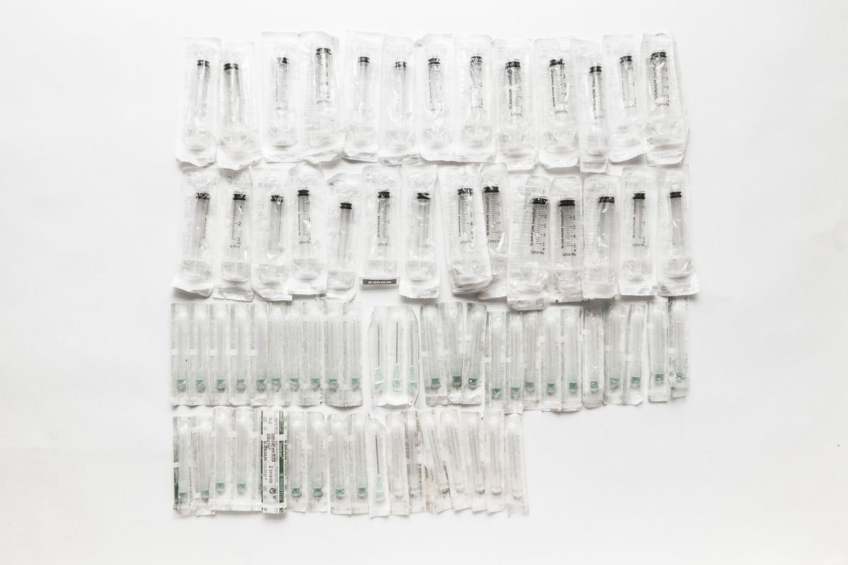 Rows of unused needles in packets on a white background.