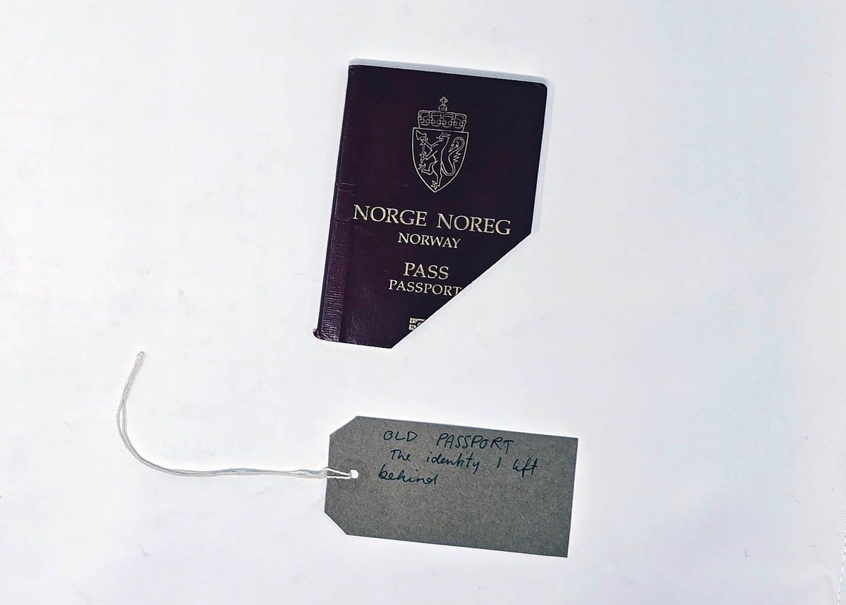 A Norwegian Passport with the bottom left corner cut off. With a brown, handwritten luggage tag.