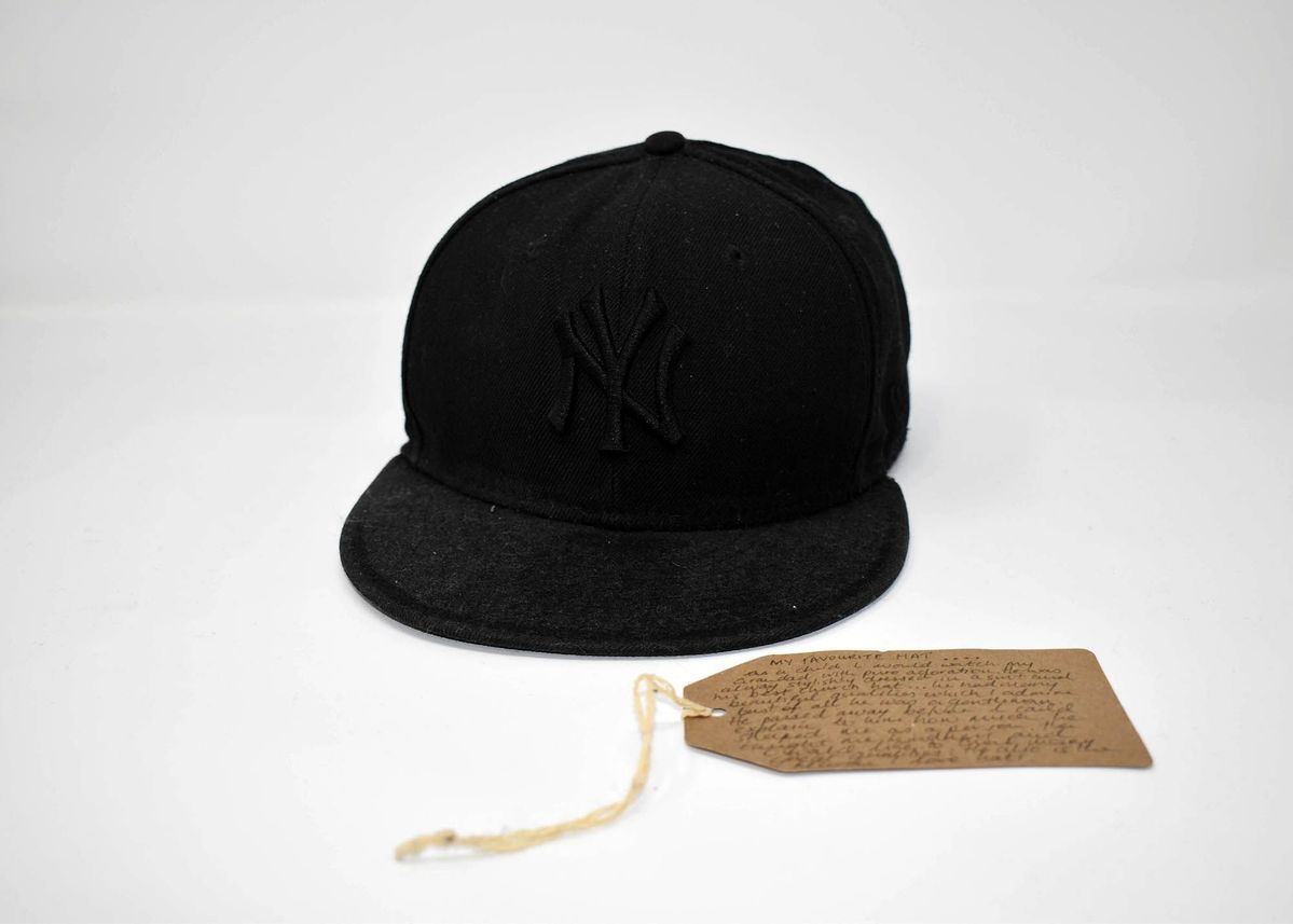 Black baseball cap lying next to a brown tag.