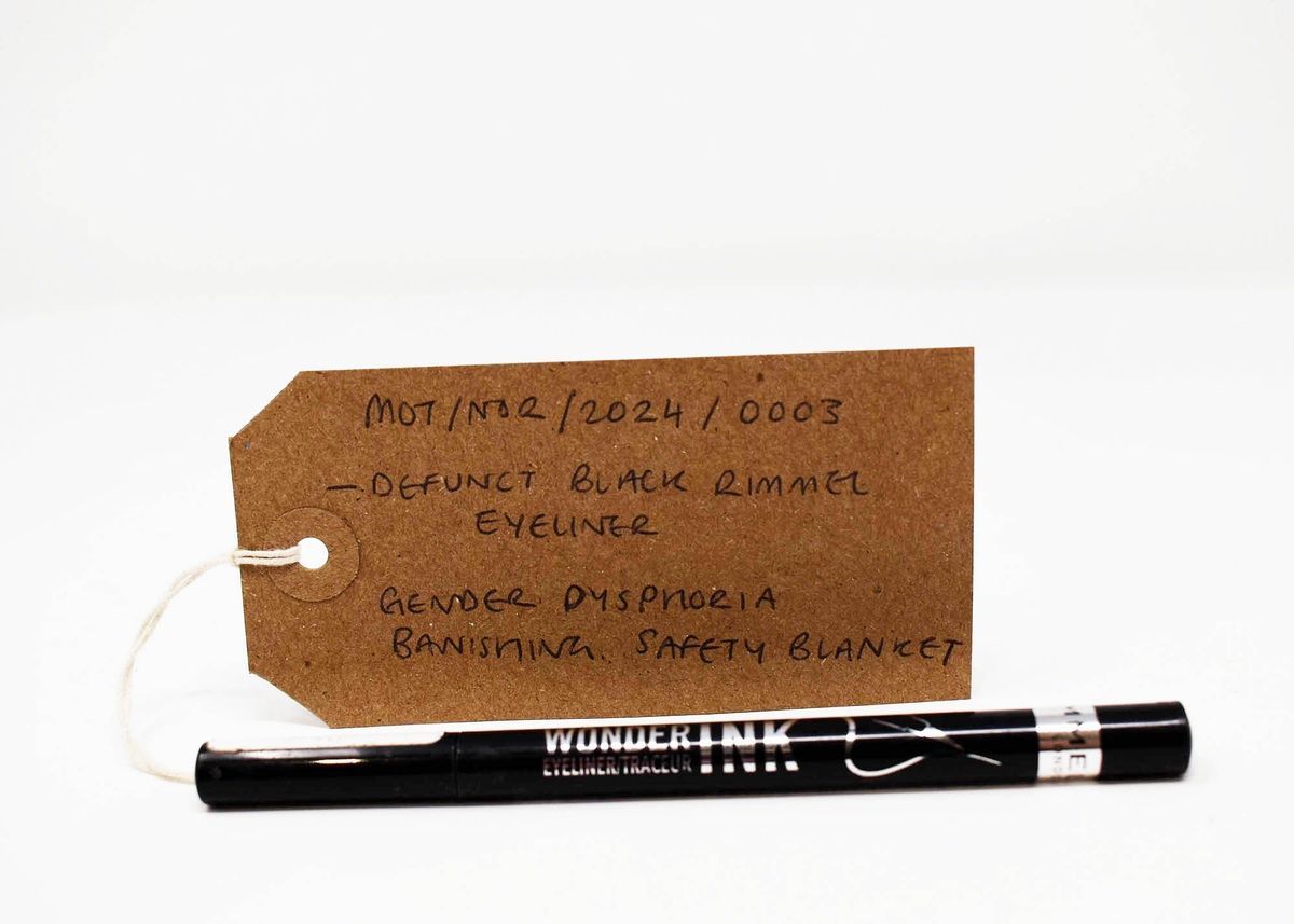 A brown tag labeled "defunct black Rimmel eyeliner" sits beside the eyeliner pen.