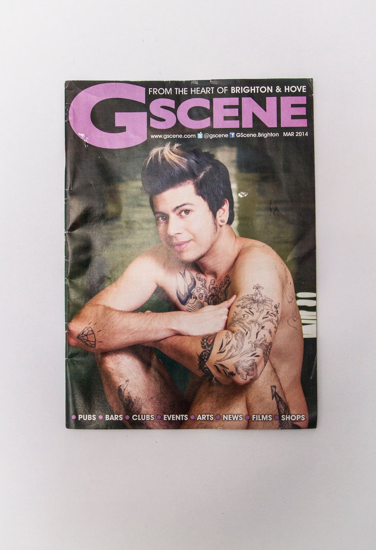 The magazine cover features a tattooed individual sitting and smiling, with "G Scene" prominently displayed above