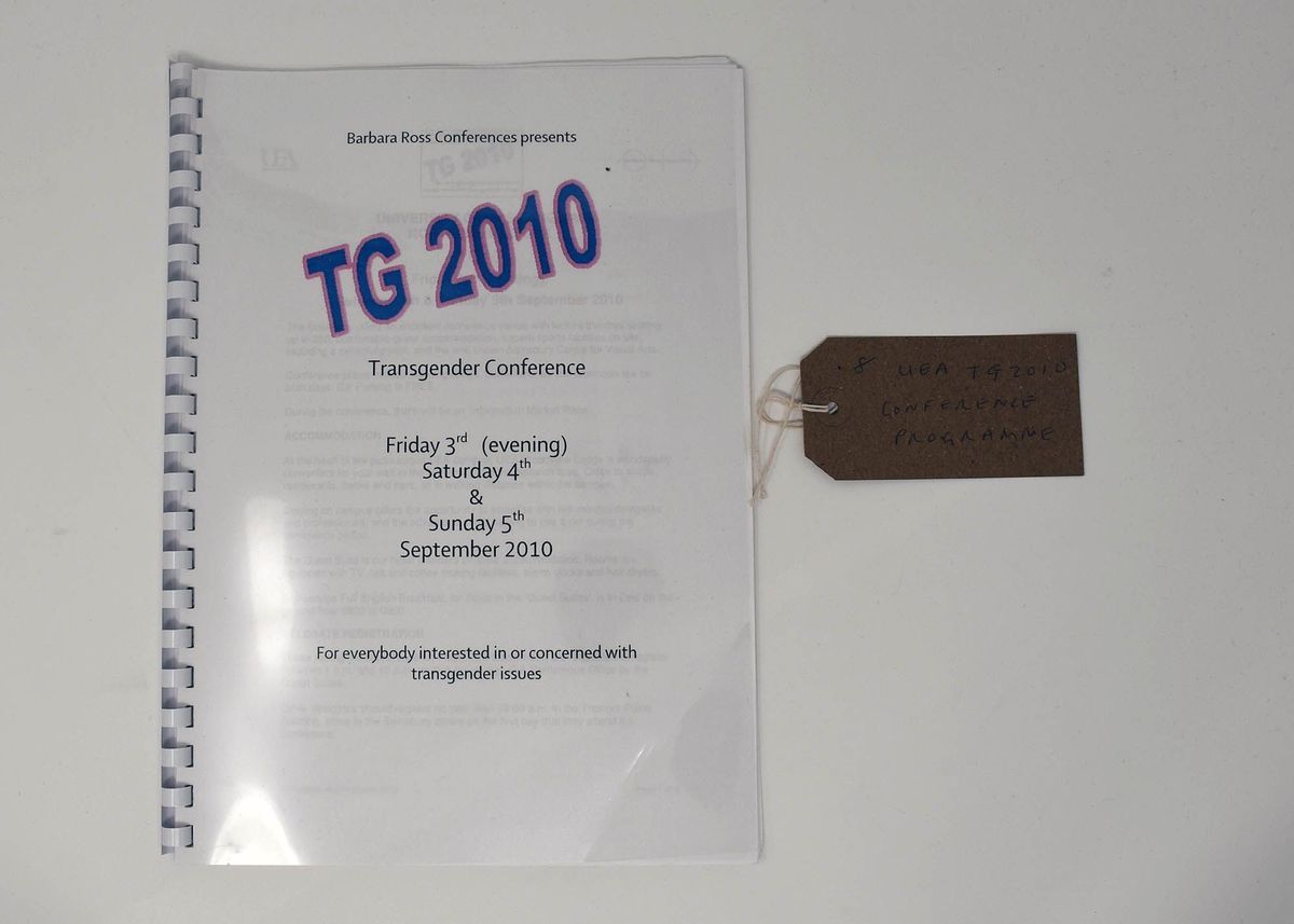 The image shows a TG 2010 Transgender Conference booklet with a tag attached.