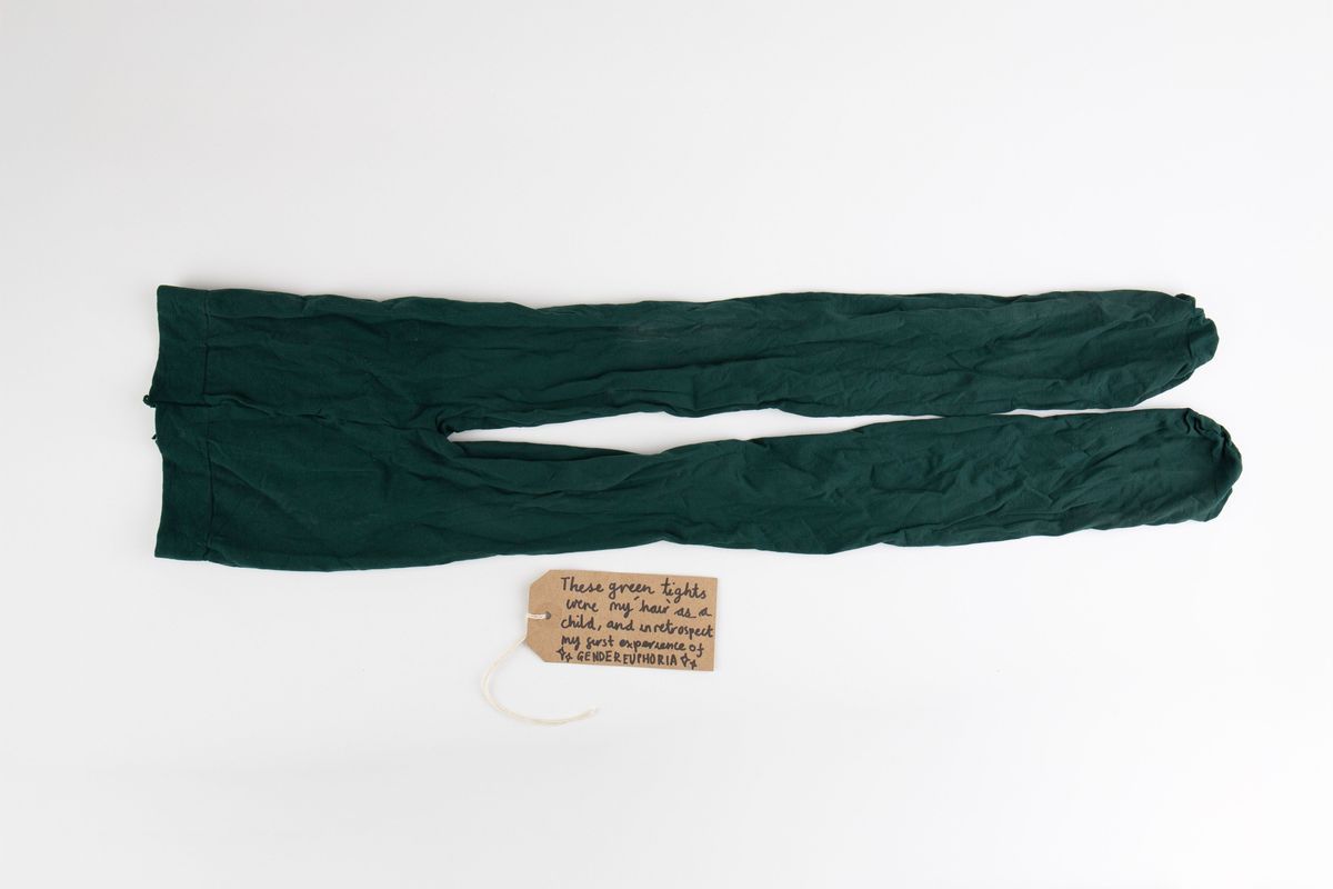 A pair of dark green opaque tights. With a brown, handwritten luggage tag.