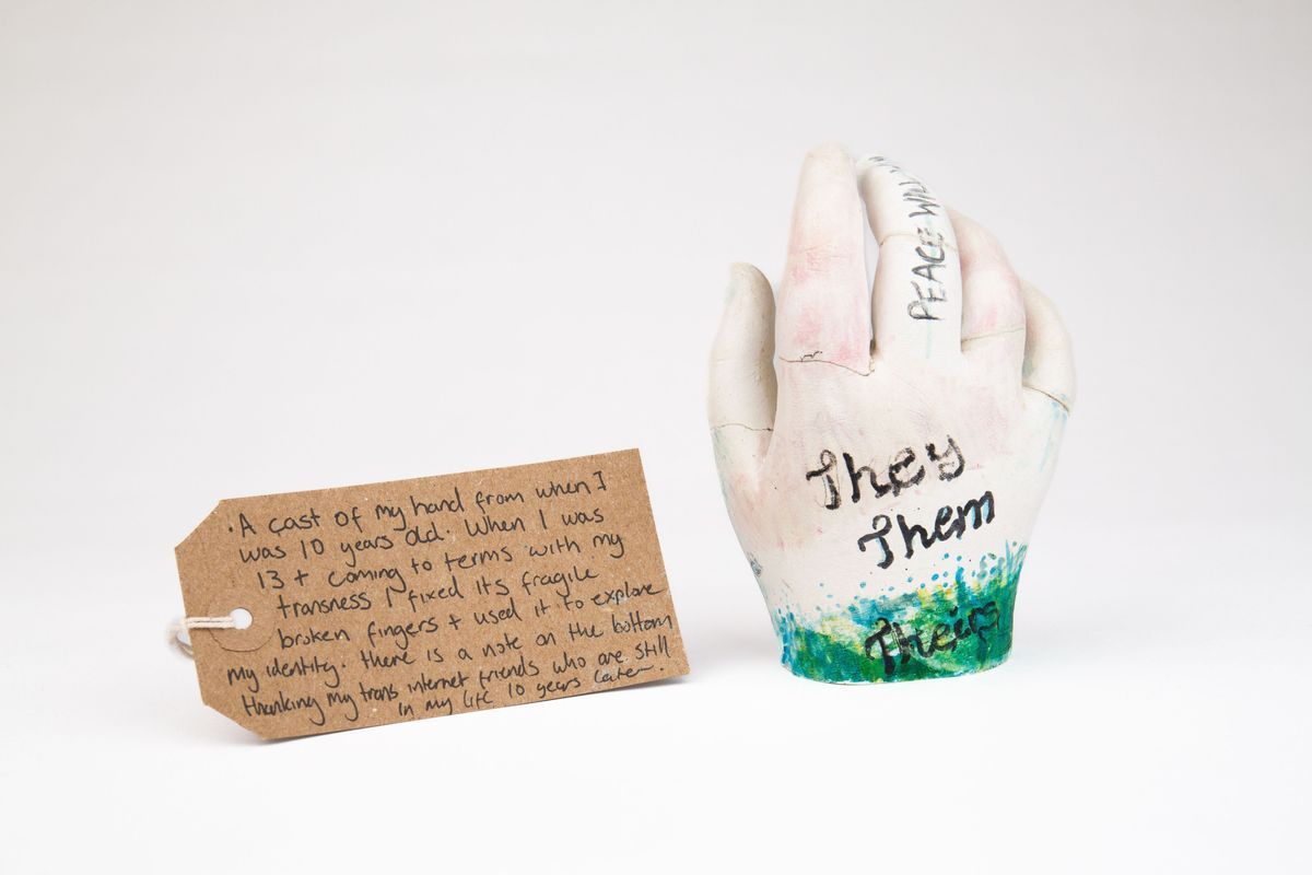 The image shows a hand cast with "They Them" written, accompanied by a handwritten note.