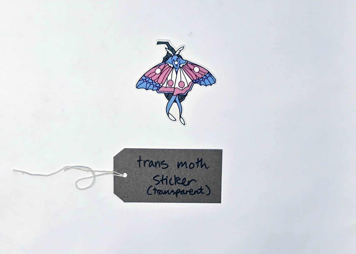 A small sticker depicting a line drawing of a moth coloured in the trans pride colors.With a brown, handwritten luggage tag.