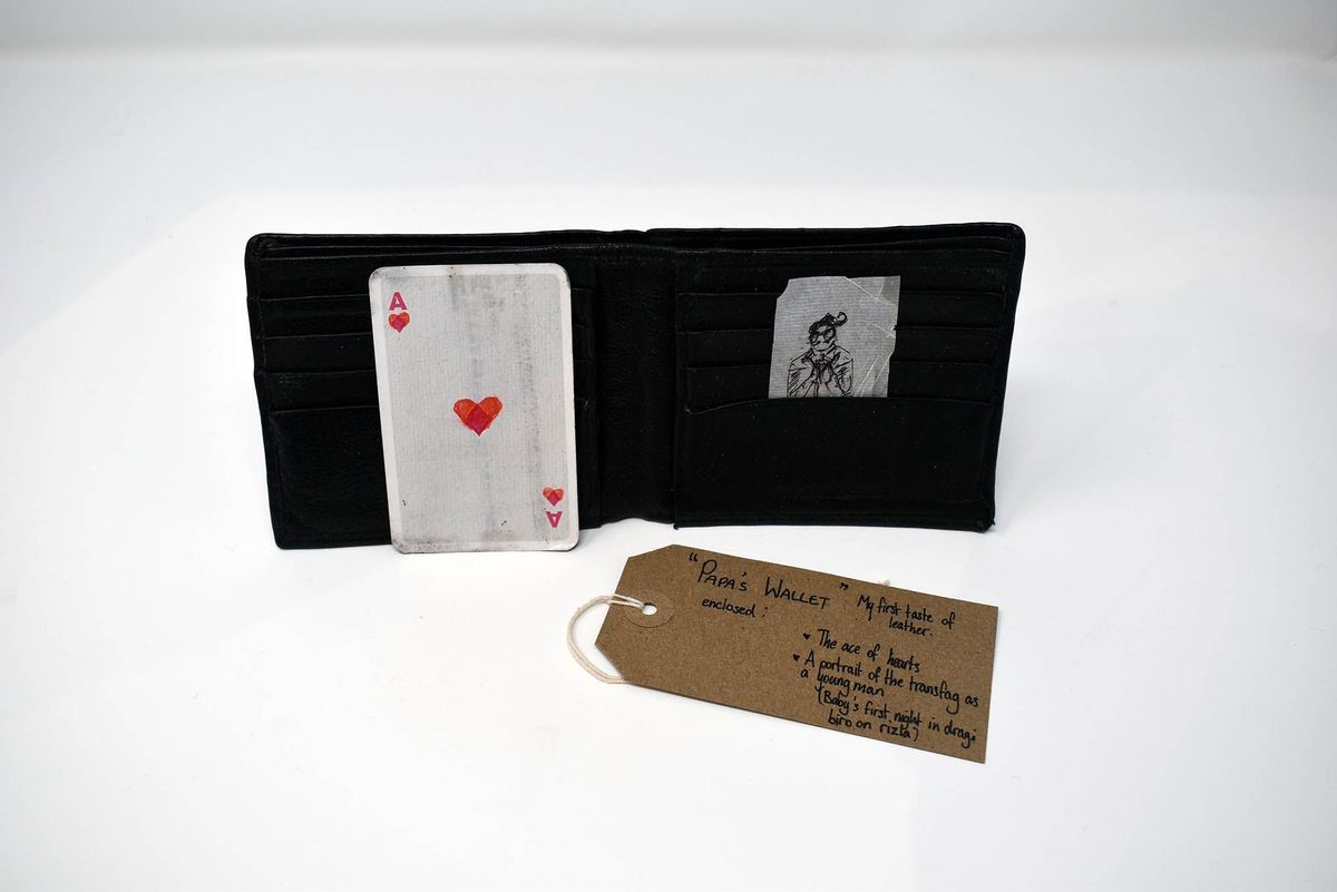 An open black wallet which has an Ace of Hearts card and a drawn portrait inside.
