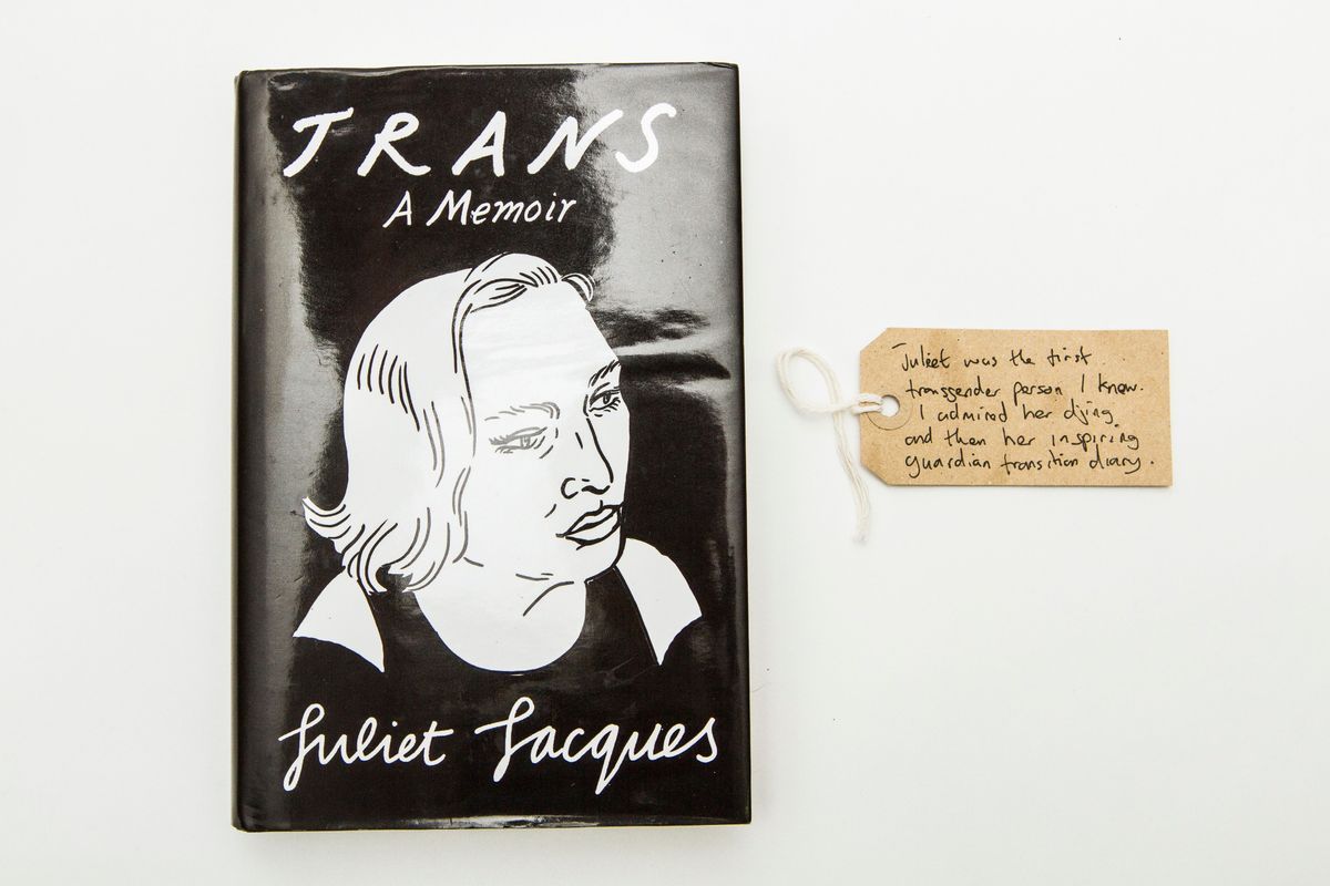 Dust cover of the book "TRANS A Memoir" by Juliet Jacques. The cover is a black background with white hand drawn outline portrait of a person with shoulder length hair.