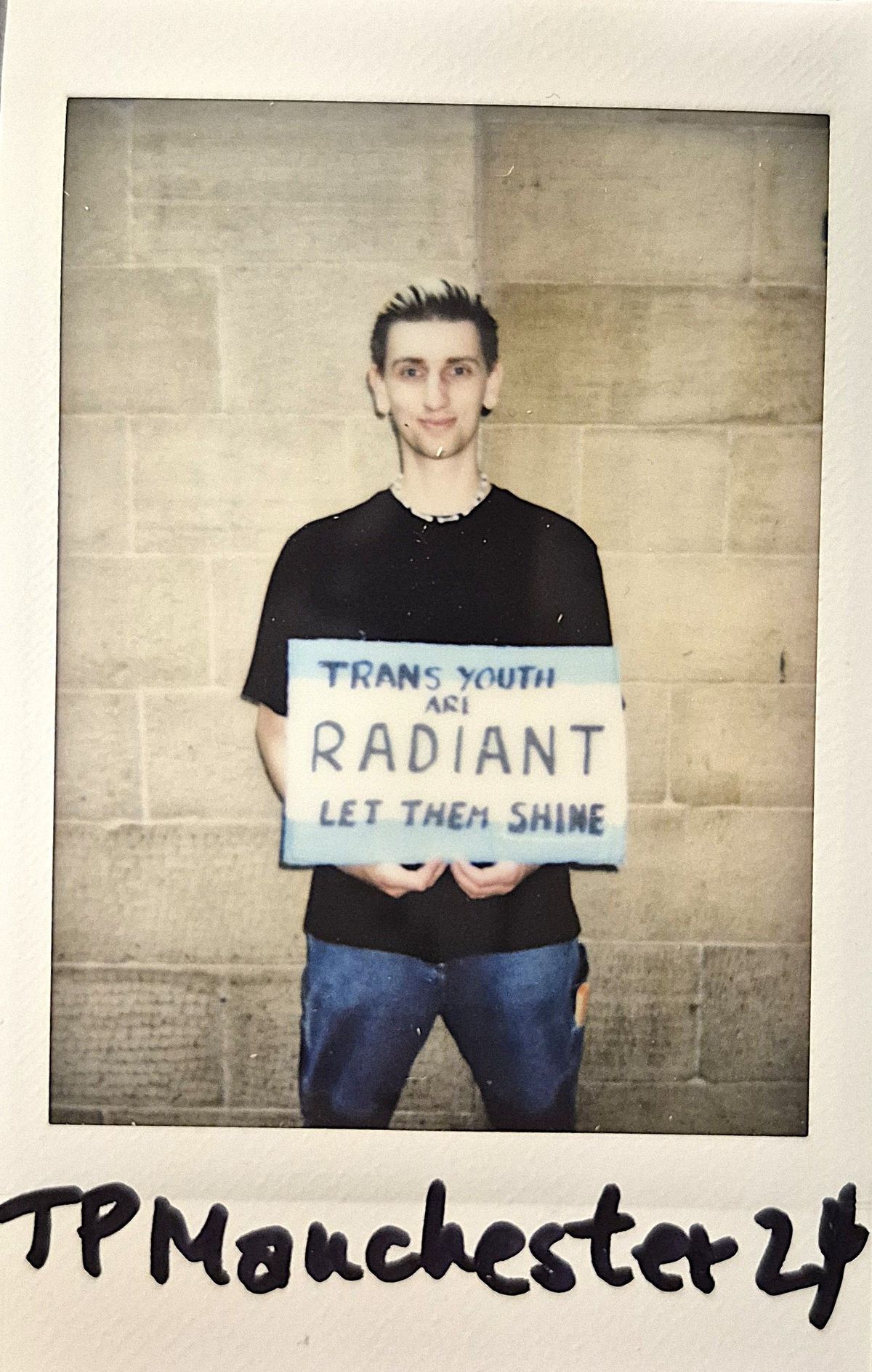 A person holds a sign advocating for trans youth.