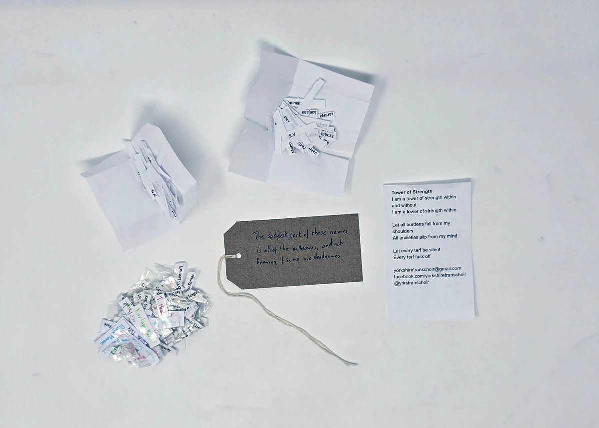 Plastic sleeve containing a bundle of small strips of paper, a poem titled "Tower of Strength", several white strips of paper, and a brown tag.