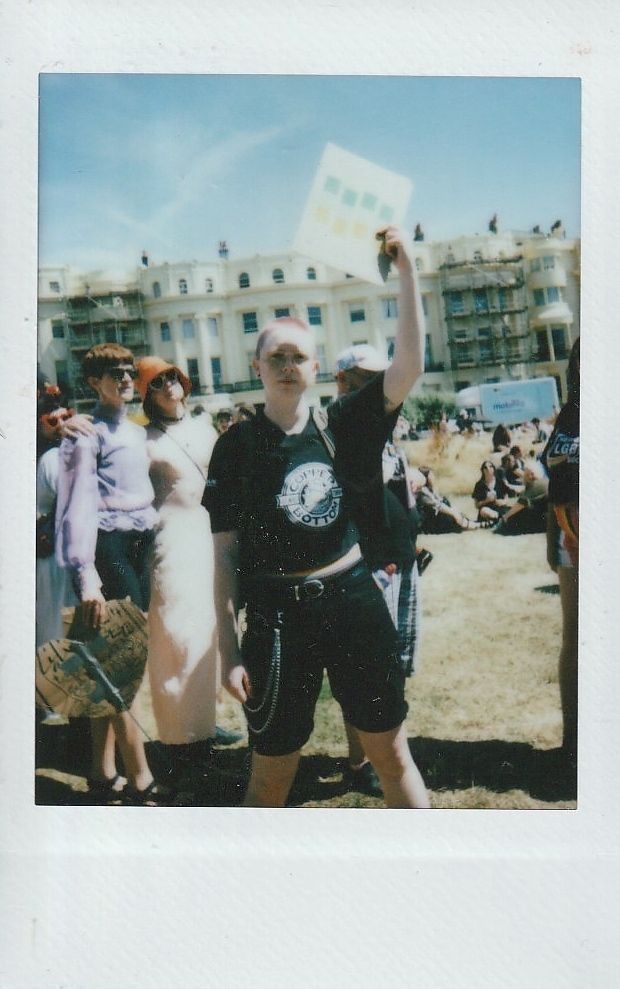 A person stands holding a sign up in the air. It is too blurry to make out what it says.
