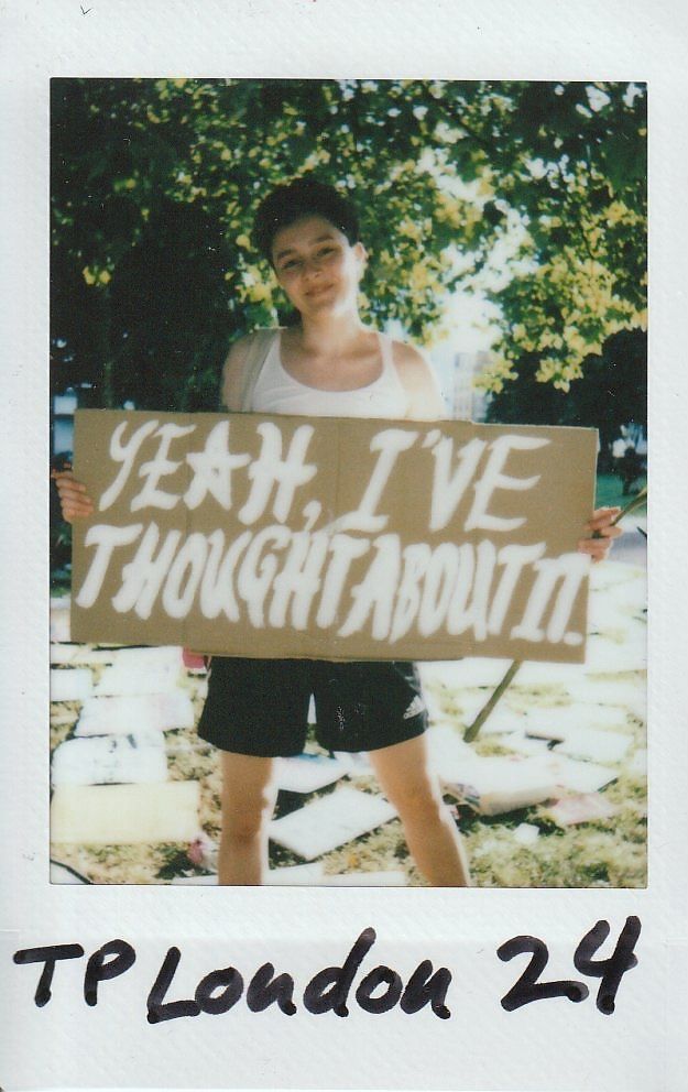 A person stands outdoors holding a sign saying, "YEAH, I'VE THOUGHT ABOUT IT".