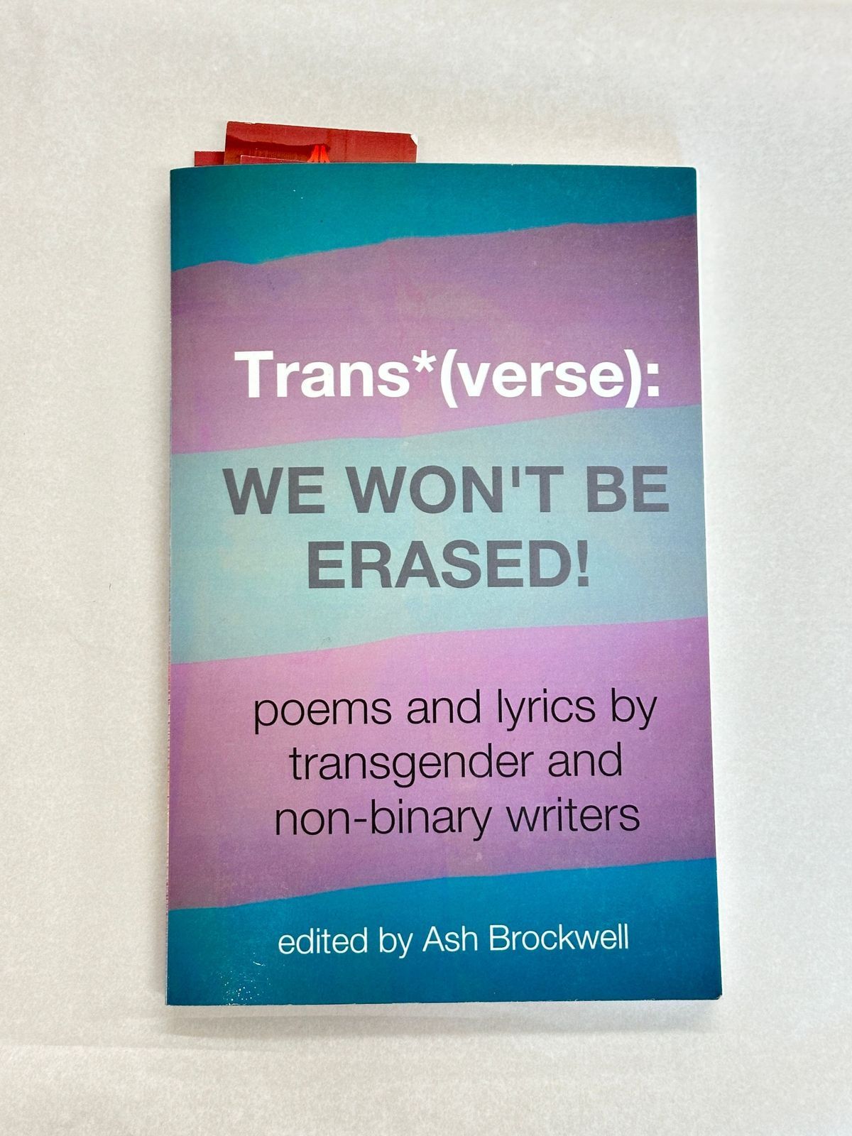 The image shows a book titled “Trans*(verse): WE WON’T BE ERASED!" featuring poetry.