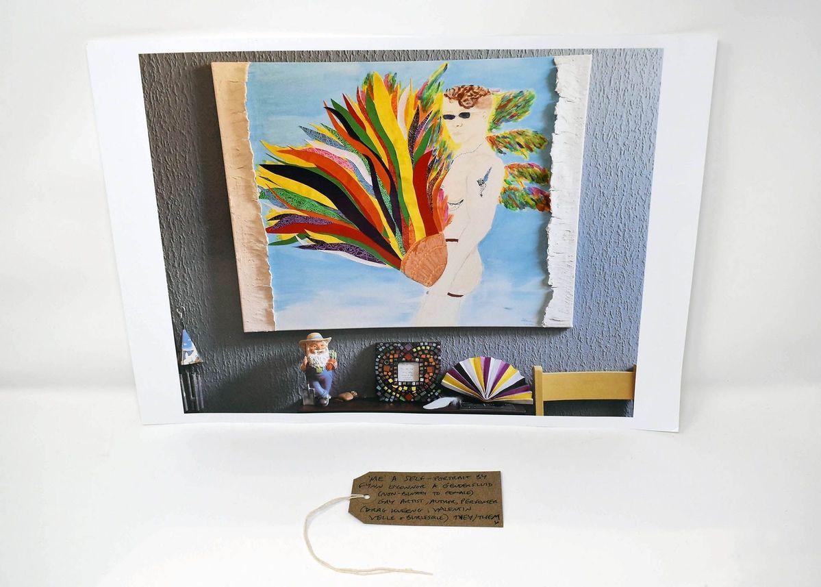 A photograph of an artwork which is hung on the wall with lots of trinkets lined up underneath. The artwork is a self portrait  of a naked person holding what looks like a basket which is bursting with colourful streams,